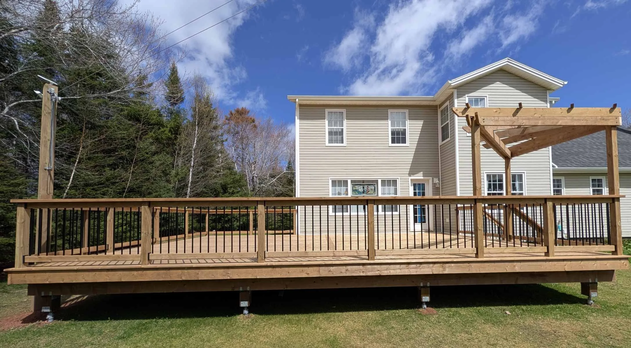 Custom design pressure treated corner wood pergola on deck with black aluminum railings built for a homeowner in Brackely Beach, PEI 
