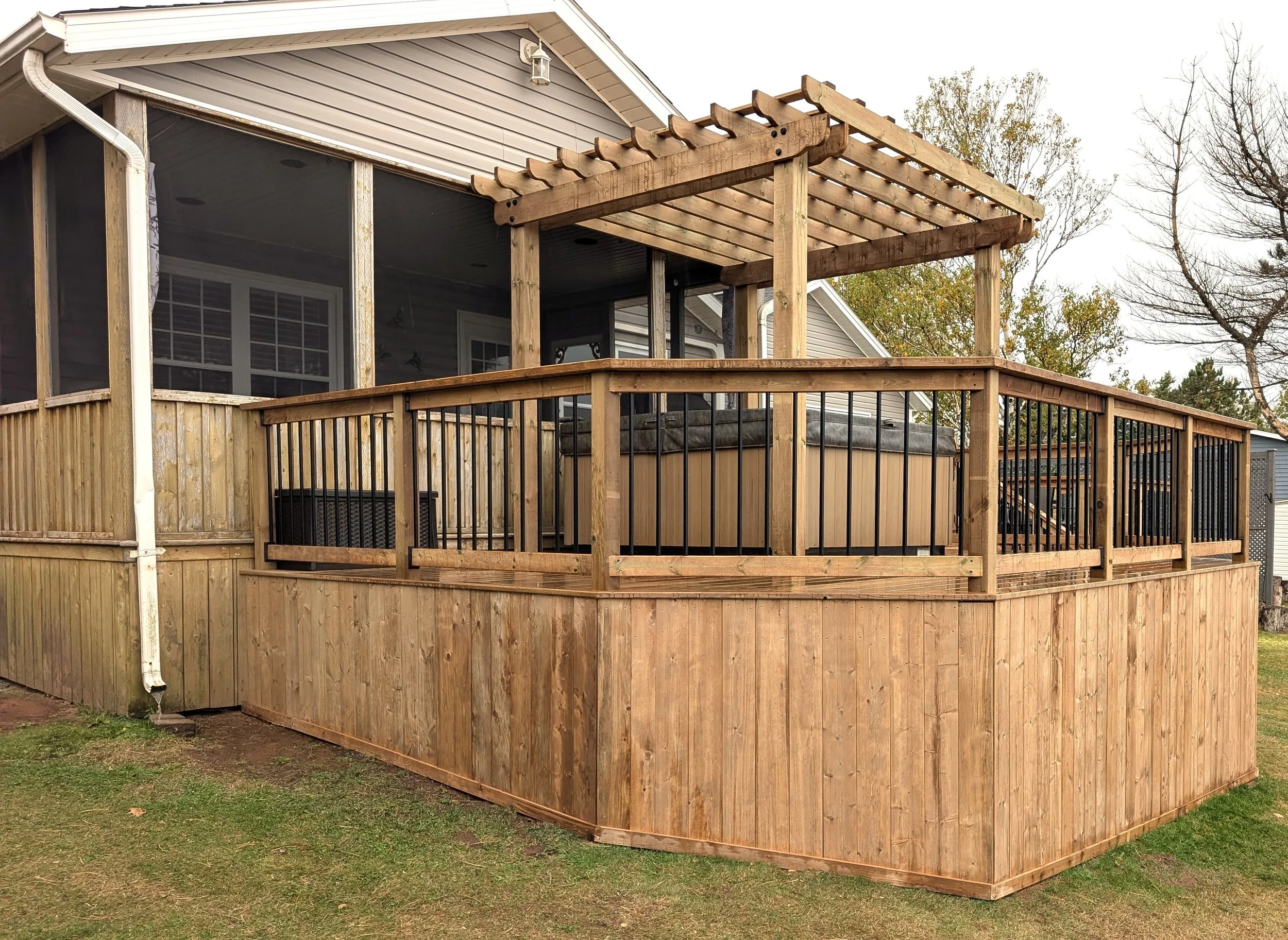 Custom design pressure treated wood pergola on multi-level deck with black aluminum railings and stairs built for a homeowner in West Covehead, PEI 