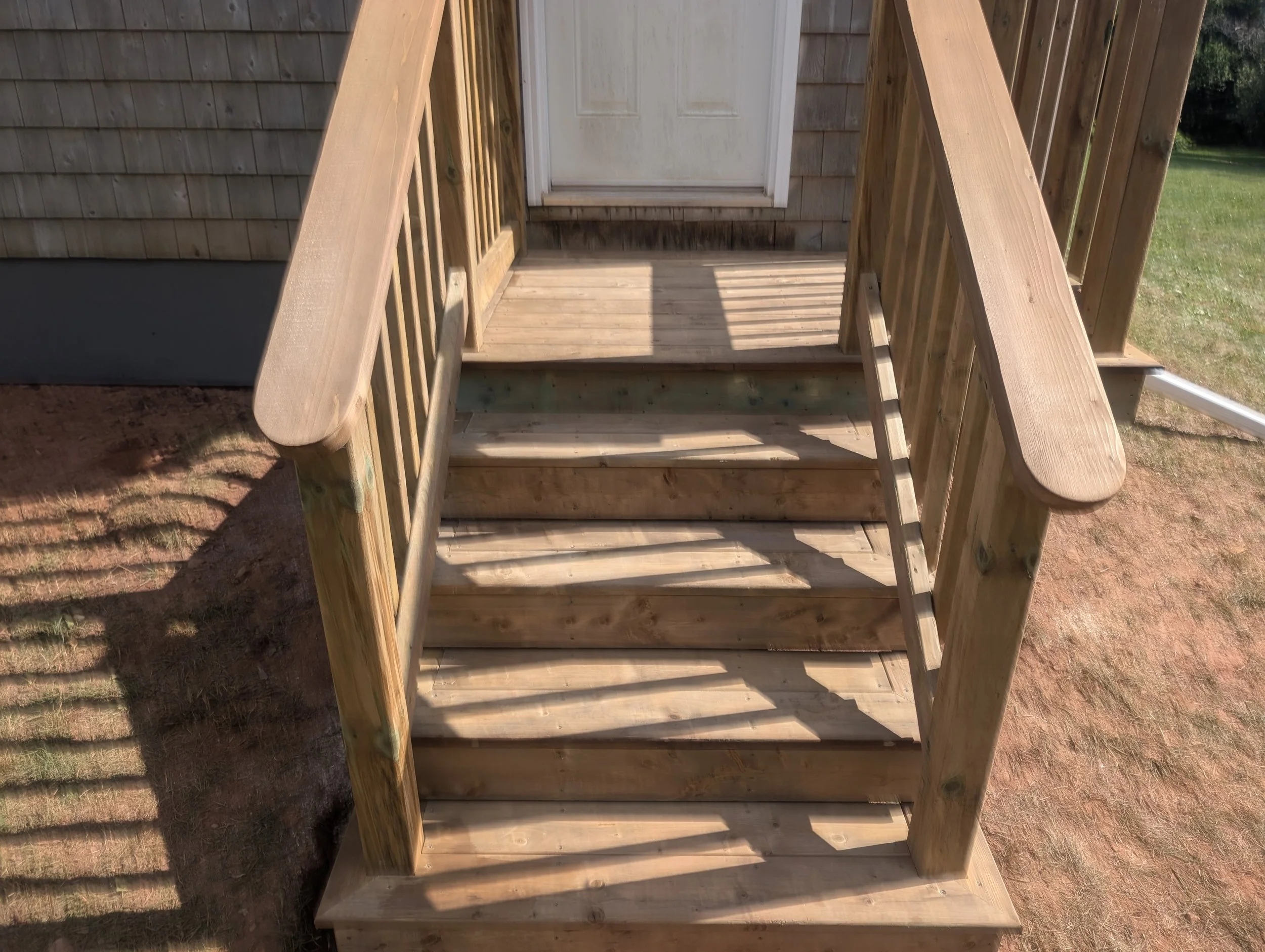Custom design and built, pressure treated, wooden deck with stairs and wood railing built for homeowner in Stanley Bridge, PEI