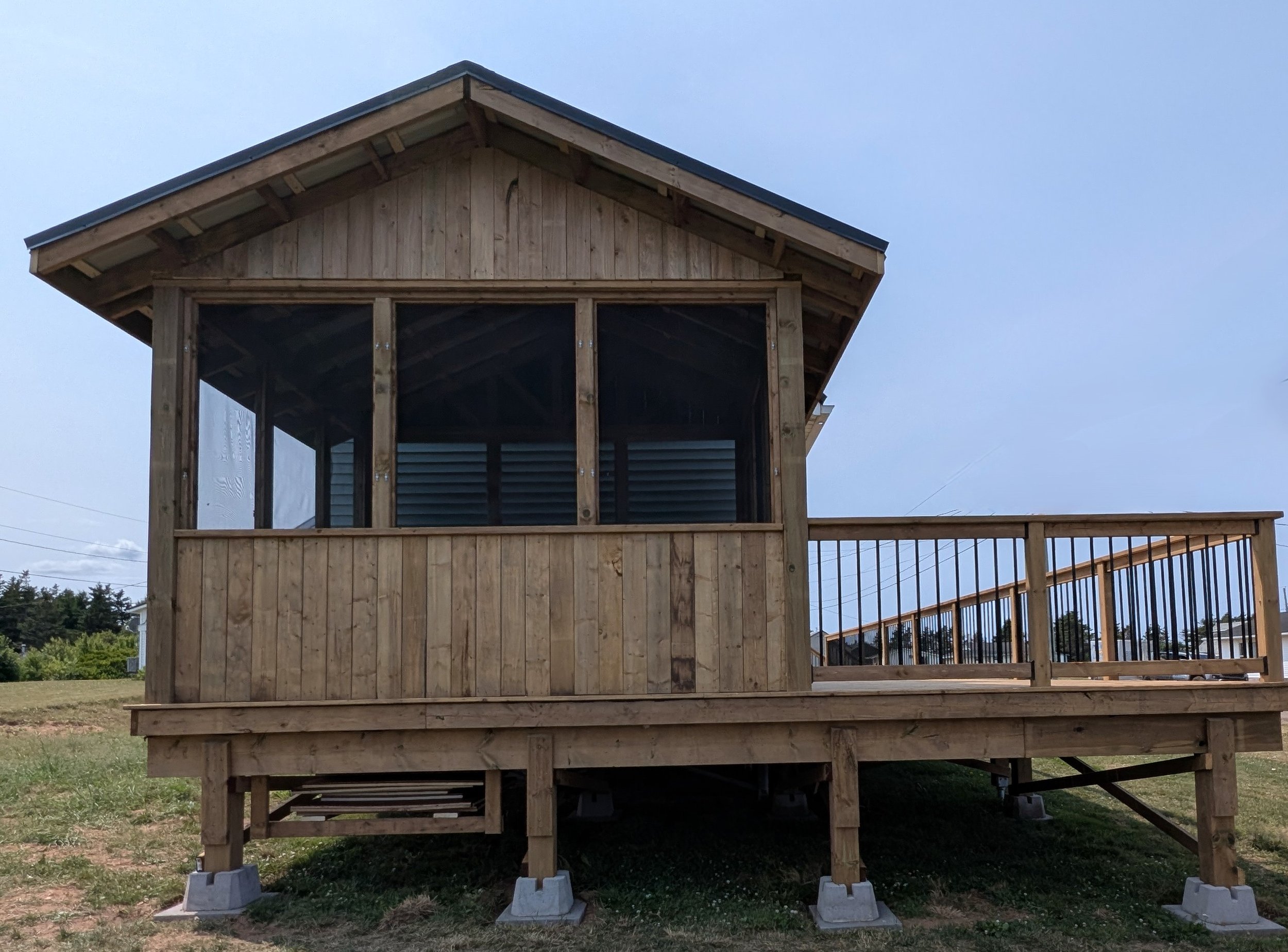 Custom design pressure treated screened in wood gazebo on deck with black aluminum railings  built for a homeowner in Wild Harbour, PEI 