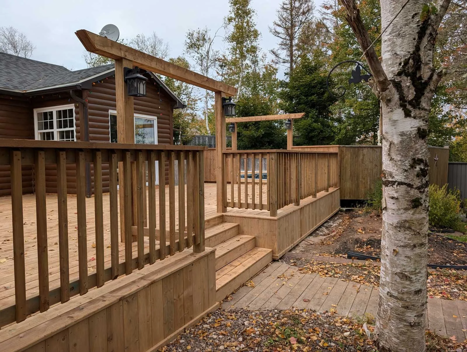 Custom built, pressure treated, multi-level wooden deck with wood railings, and inset step, built for a homeowner in Hunter River, PEI.