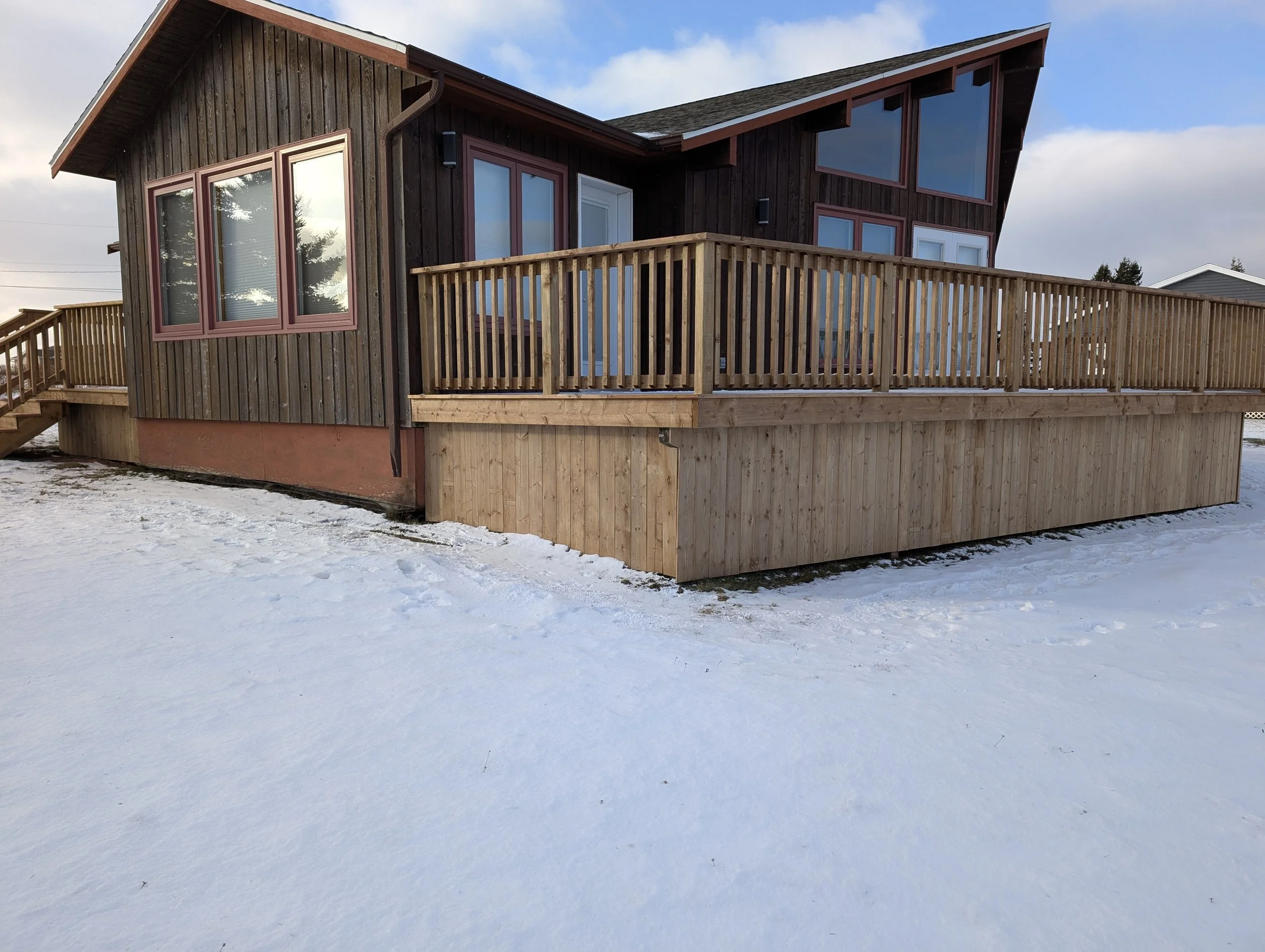Custom built, pressure treated wooden deck with wood railings and stairs, built for a cottage owner in Stanley Bridge, PEI