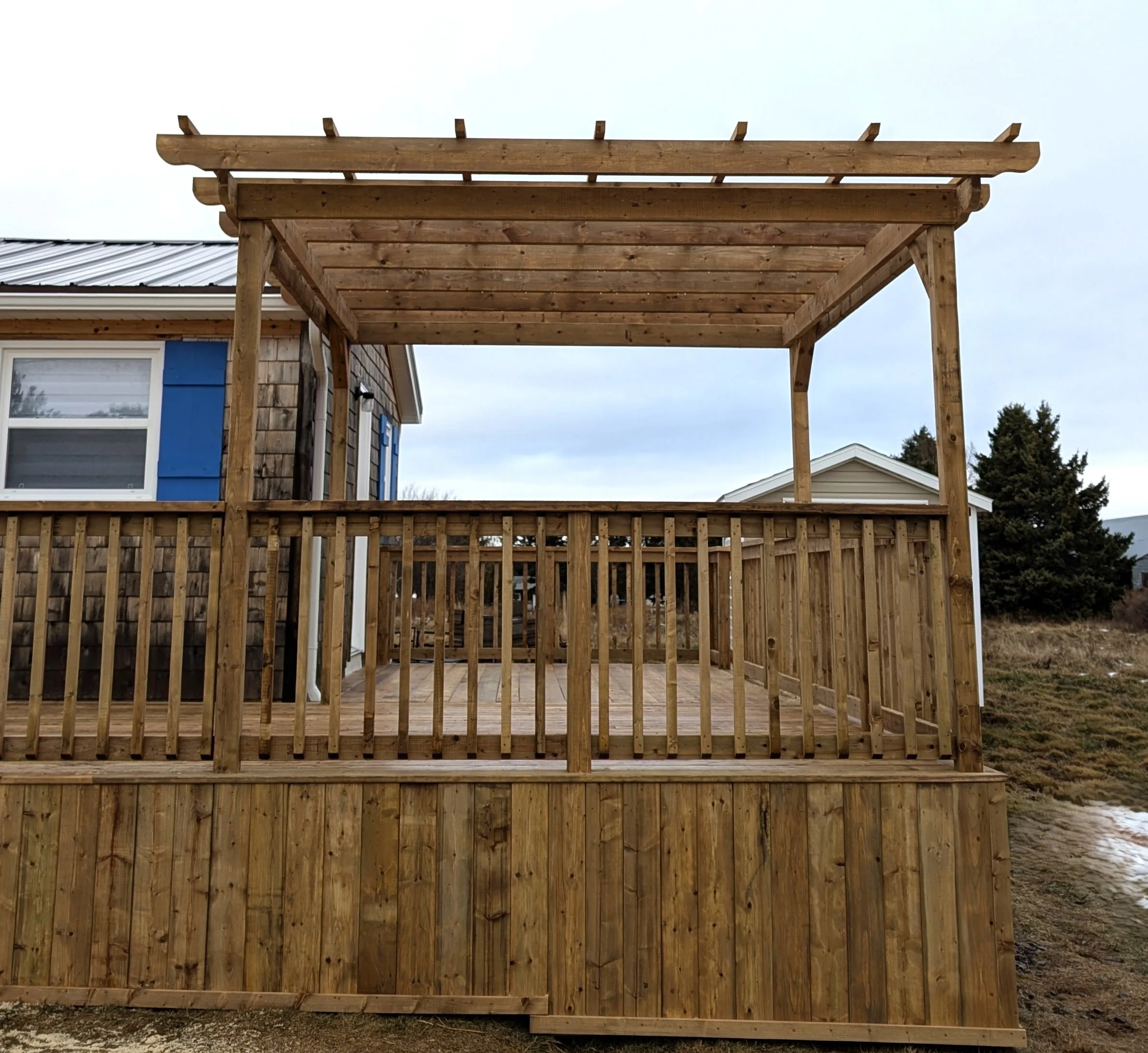 Custom pressure treated wooden deck with wood pergola and railings built for a cottage owner in Canoe Cove, PEI