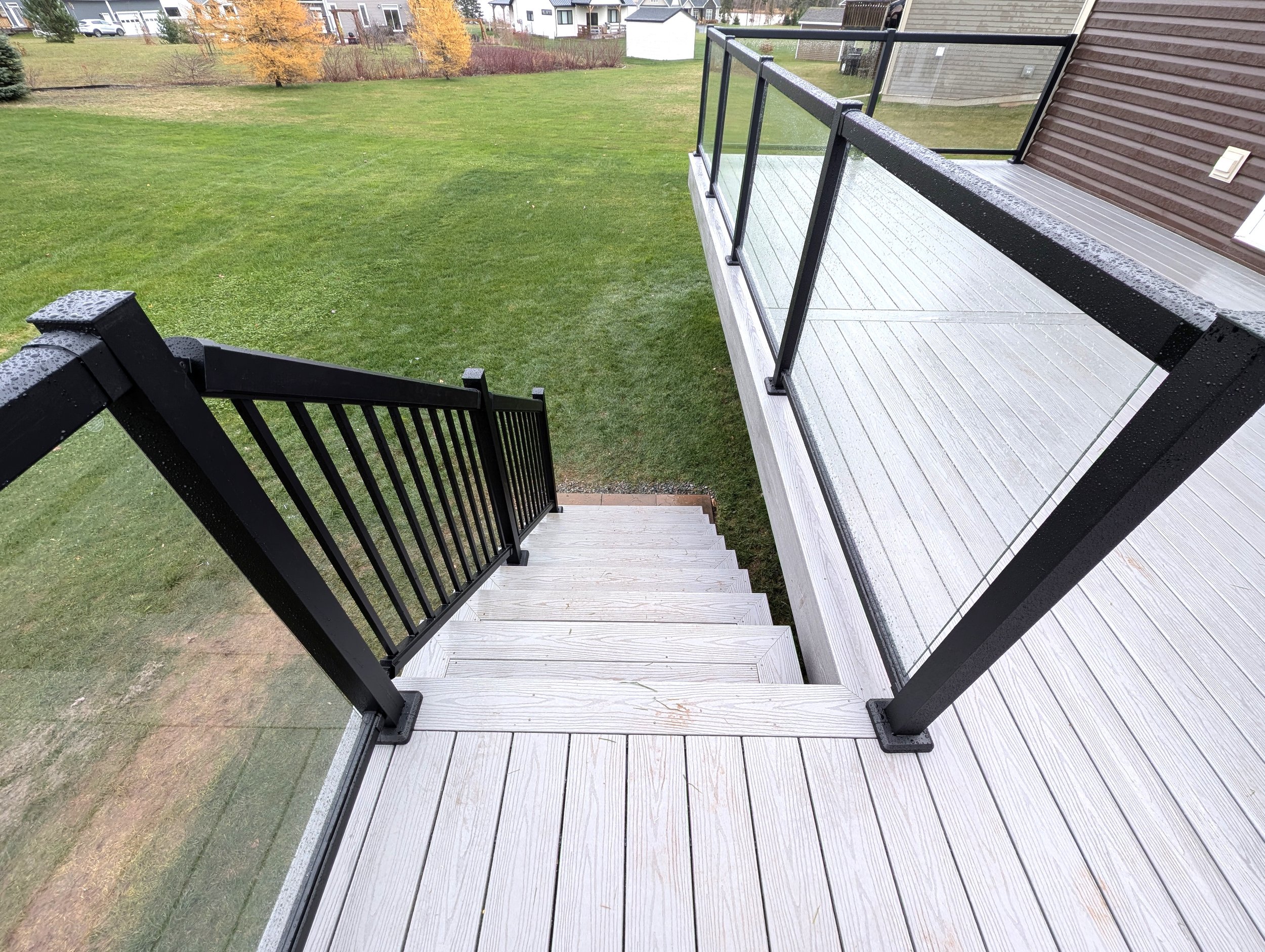 Custom design and built, grey composite deck with stairs, black aluminum & glass railing built for homeowner in Cornwall, PEI