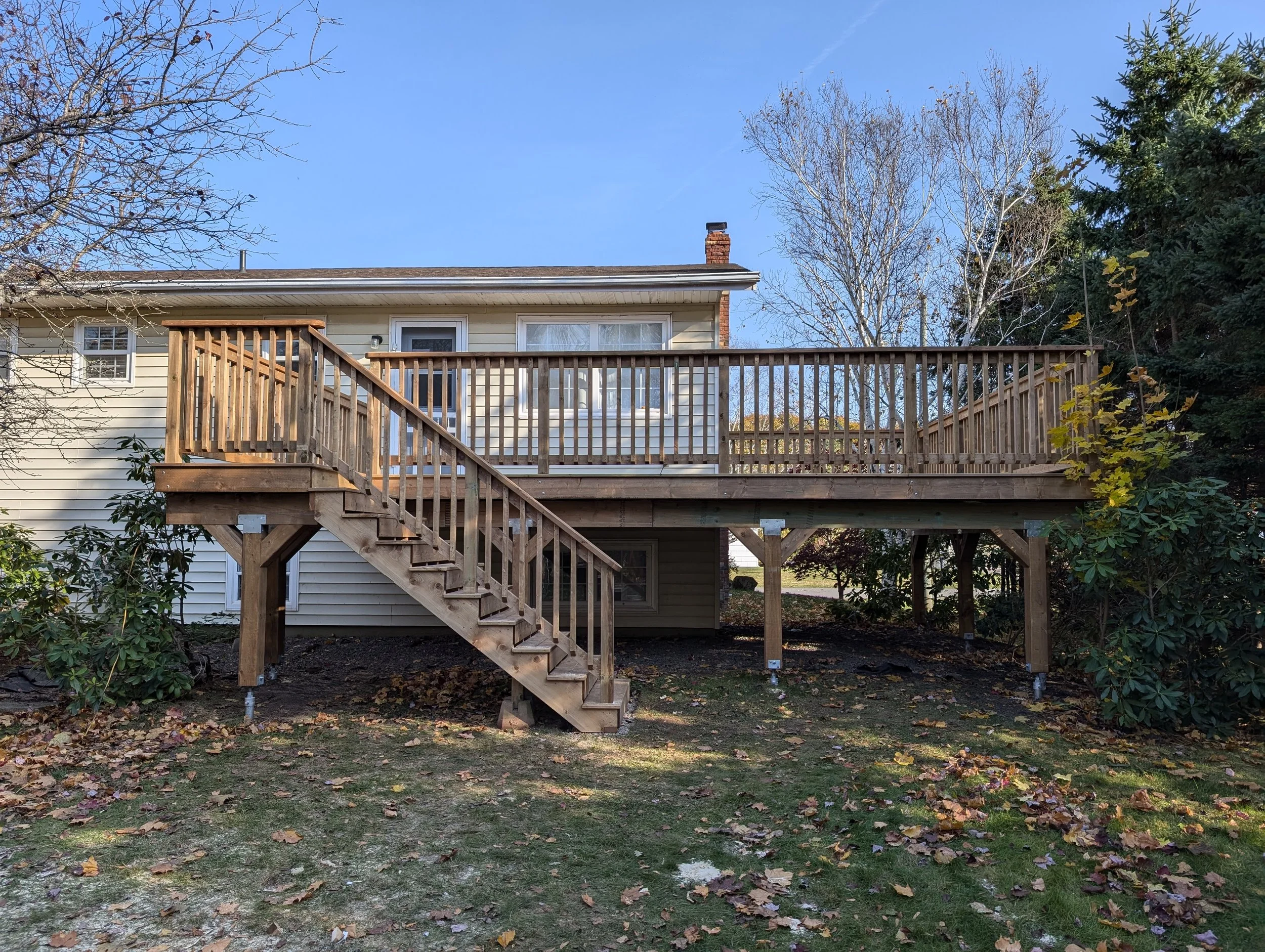 Custom built, pressure treated, upper-level wooden deck with wood railings, and stairs built for a homeowner in Stratford, PEI.
