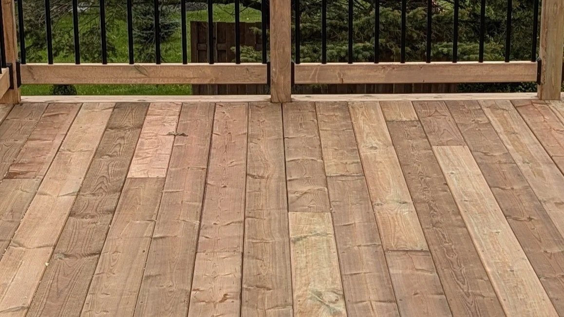 Completed pressure-treated wooden deck and railings with black aluminum railings, built in Prince Edward Island