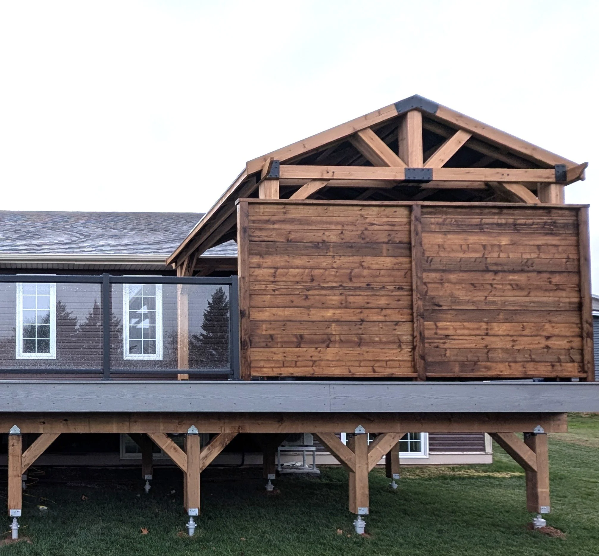 Custom design pressure treated wood corner privacy wall on composite deck with glass & black aluminum railings built for a homeowner in COrnwall, PEI 