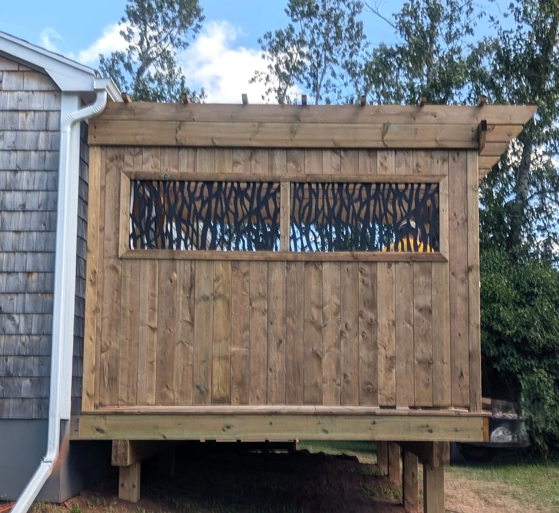 Custom pressure treated wood pergola with privacy insert built for a homeowner in Trout River, PEI 