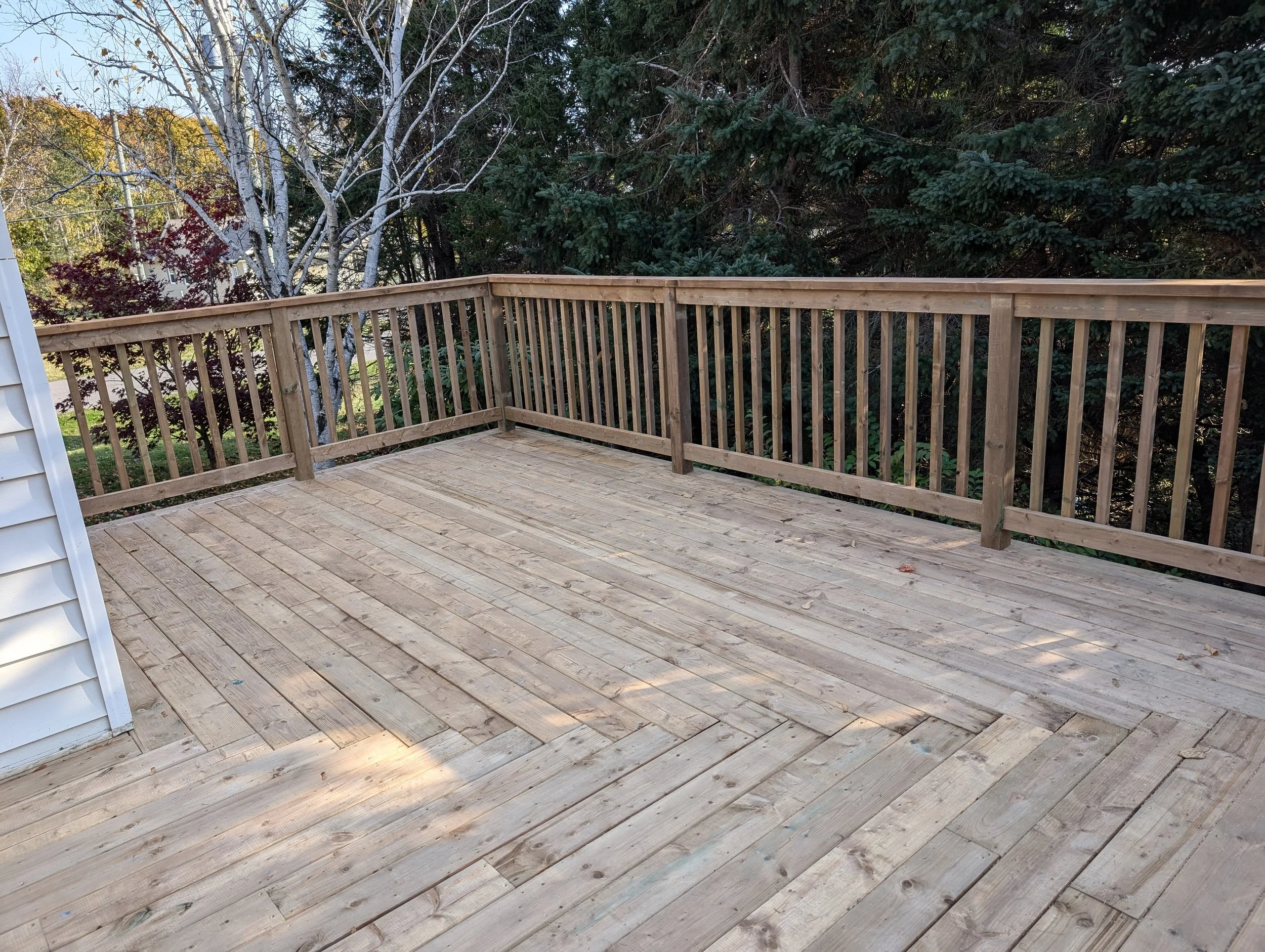 Custom built, pressure treated, upper-level wooden deck with wood railings, and stairs built for a homeowner in Stratford, PEI