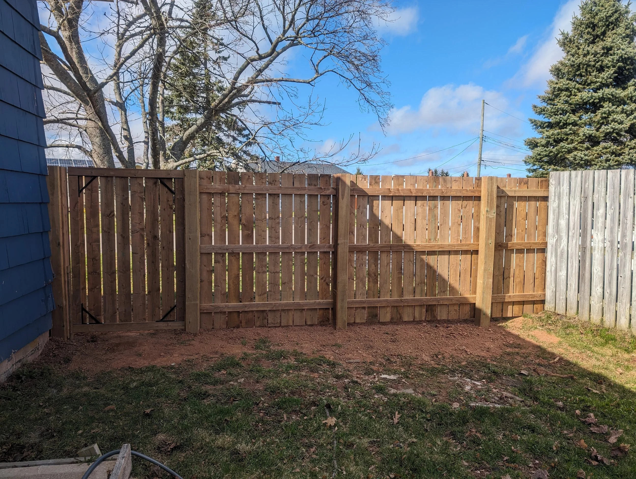 Custom pressure-treated wooden fence joining an existing structure built in Charlottetown, PEI