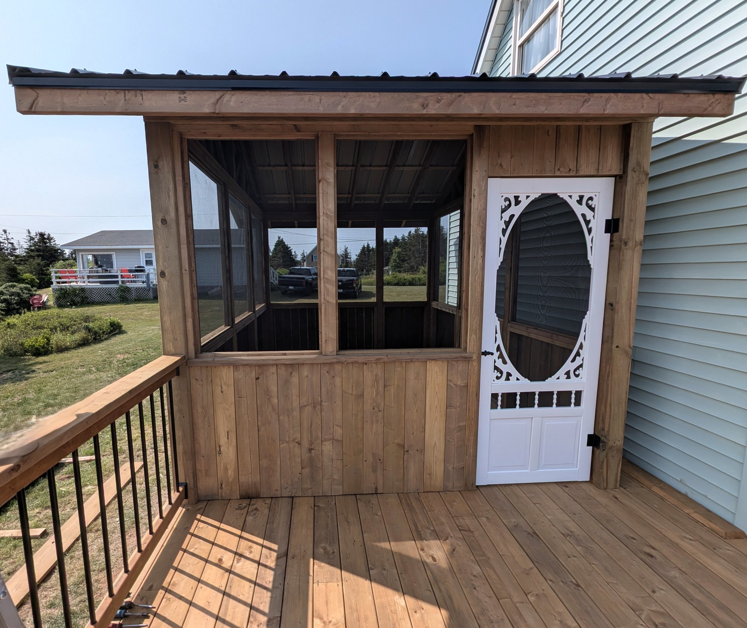 Custom design pressure treated screened in wood gazebo on deck with black aluminum railings  built for a homeowner in Wild Harbour, PEI 