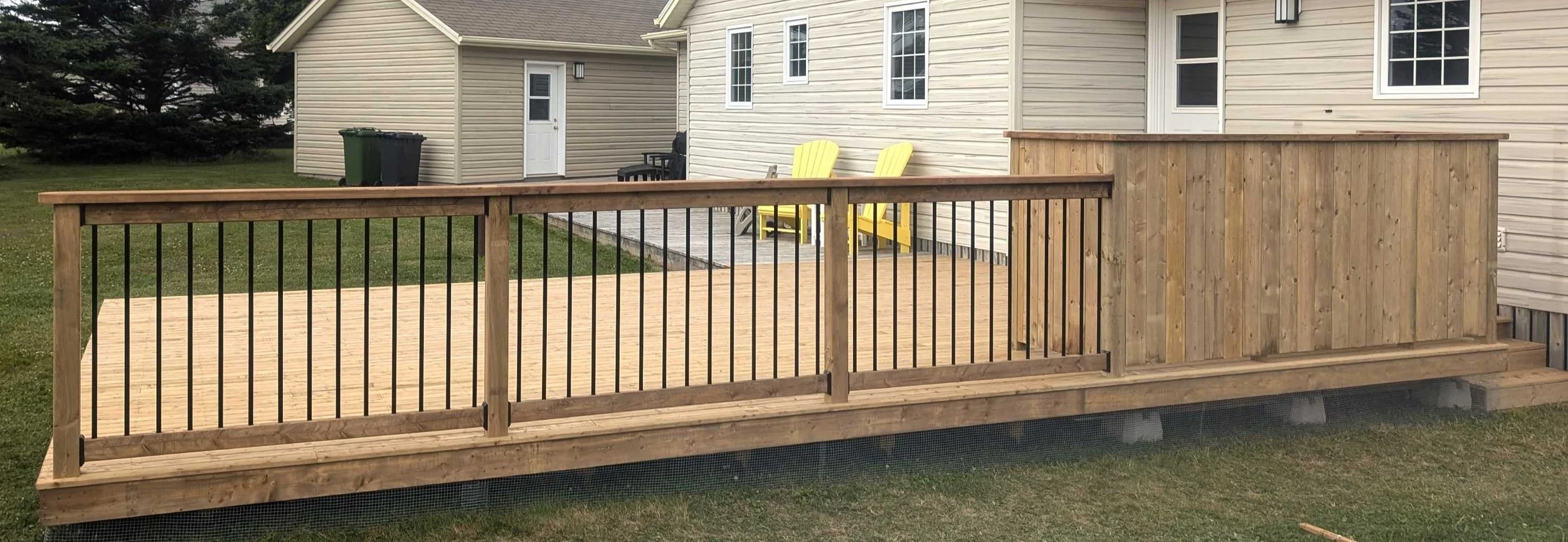 Custom designed and built pressure treated wood and black aluminum railings on deck built for cottage owner in Stanley Bridge, PEI.