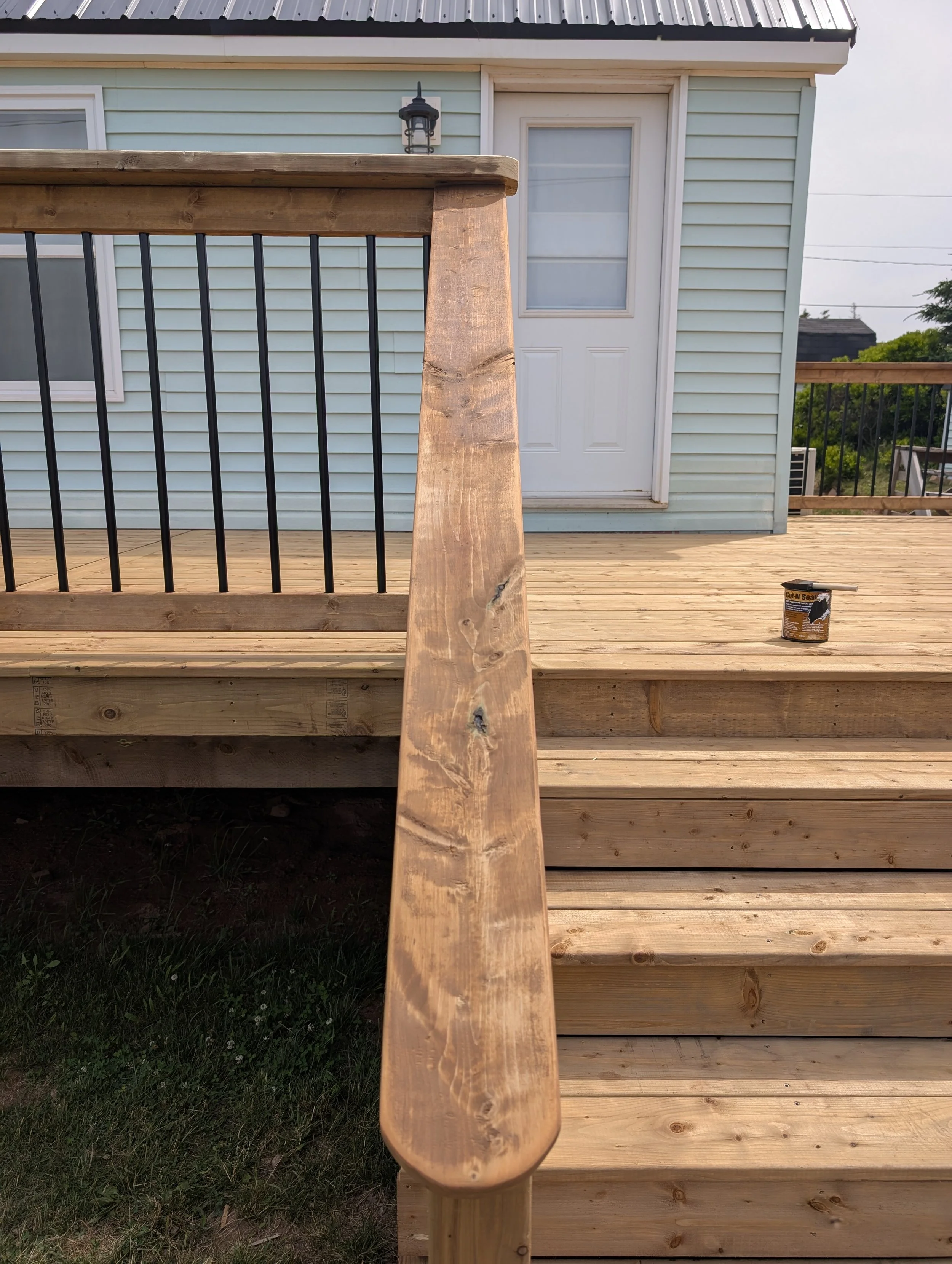Treatment for cut ends on all our decks at Island Decks including the custom design  pressure treated wooden deck with wide stairs and black aluminum railing built for homeowner in Wild Harbour, PEI