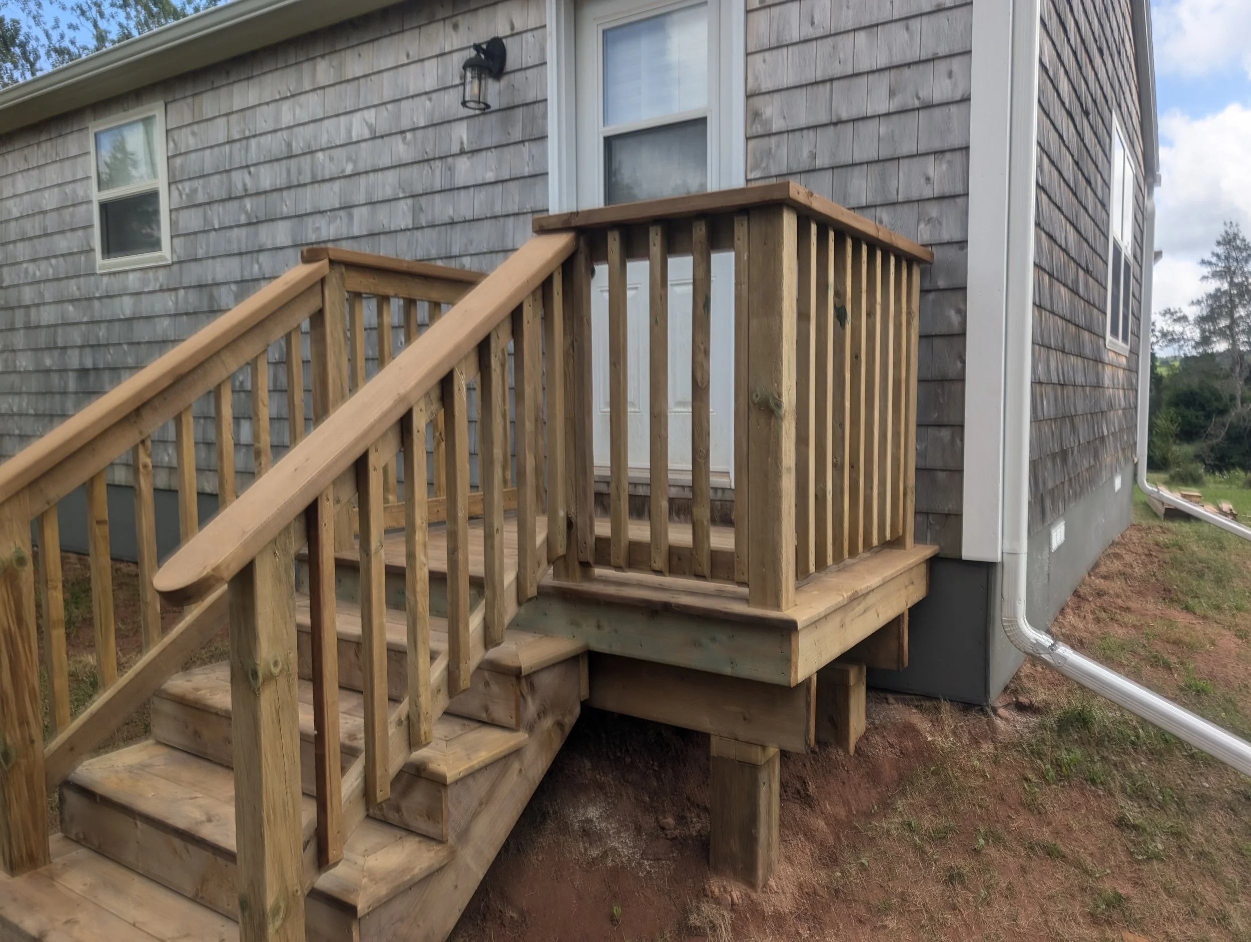Custom design and built, pressure treated, wooden deck with stairs and wood railing built for homeowner in Stanley Bridge, PEI