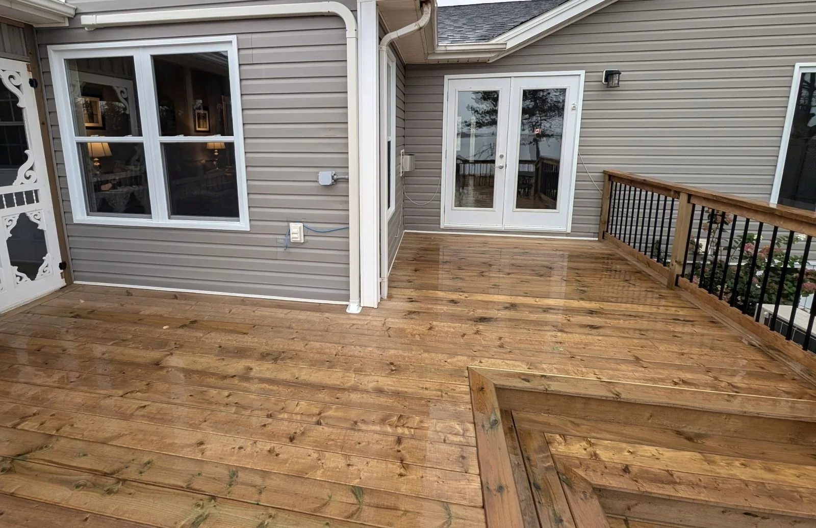 Custom built, pressure treated wooden multi-level deck with pergola over the hot tub,  black aluminum railings, under deck storage and inset stairs built for a home owner in West Covehead, PEI