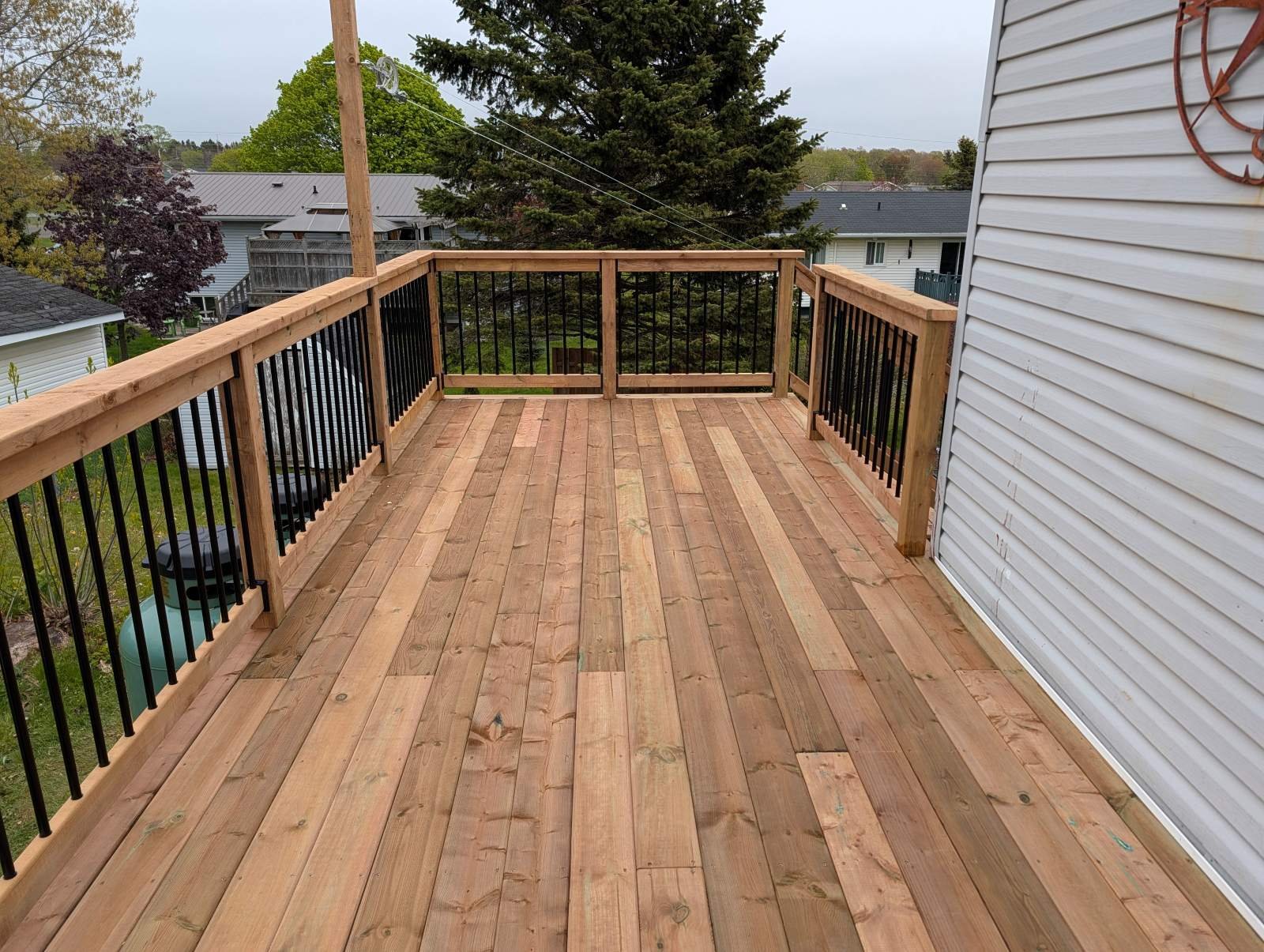 Custom designed and built pressure treated wood and black aluminum railings on deck built for home owner in Charlottetown, PEI.
