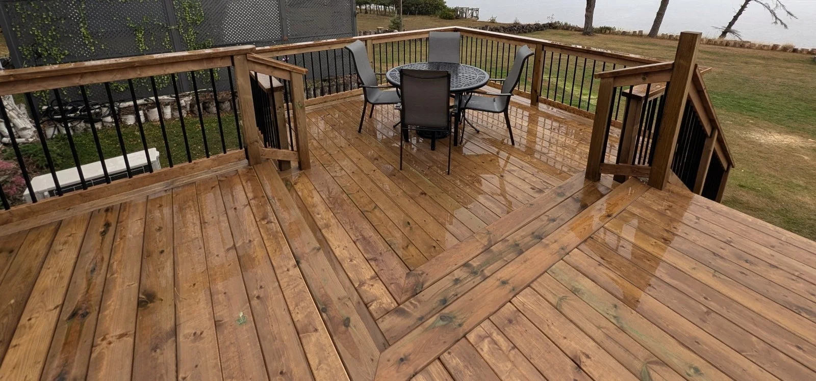 Custom built, pressure treated wooden multi-level deck with pergola over the hot tub,  black aluminum railings, under deck storage and inset stairs built for a home owner in West Covehead, PEI