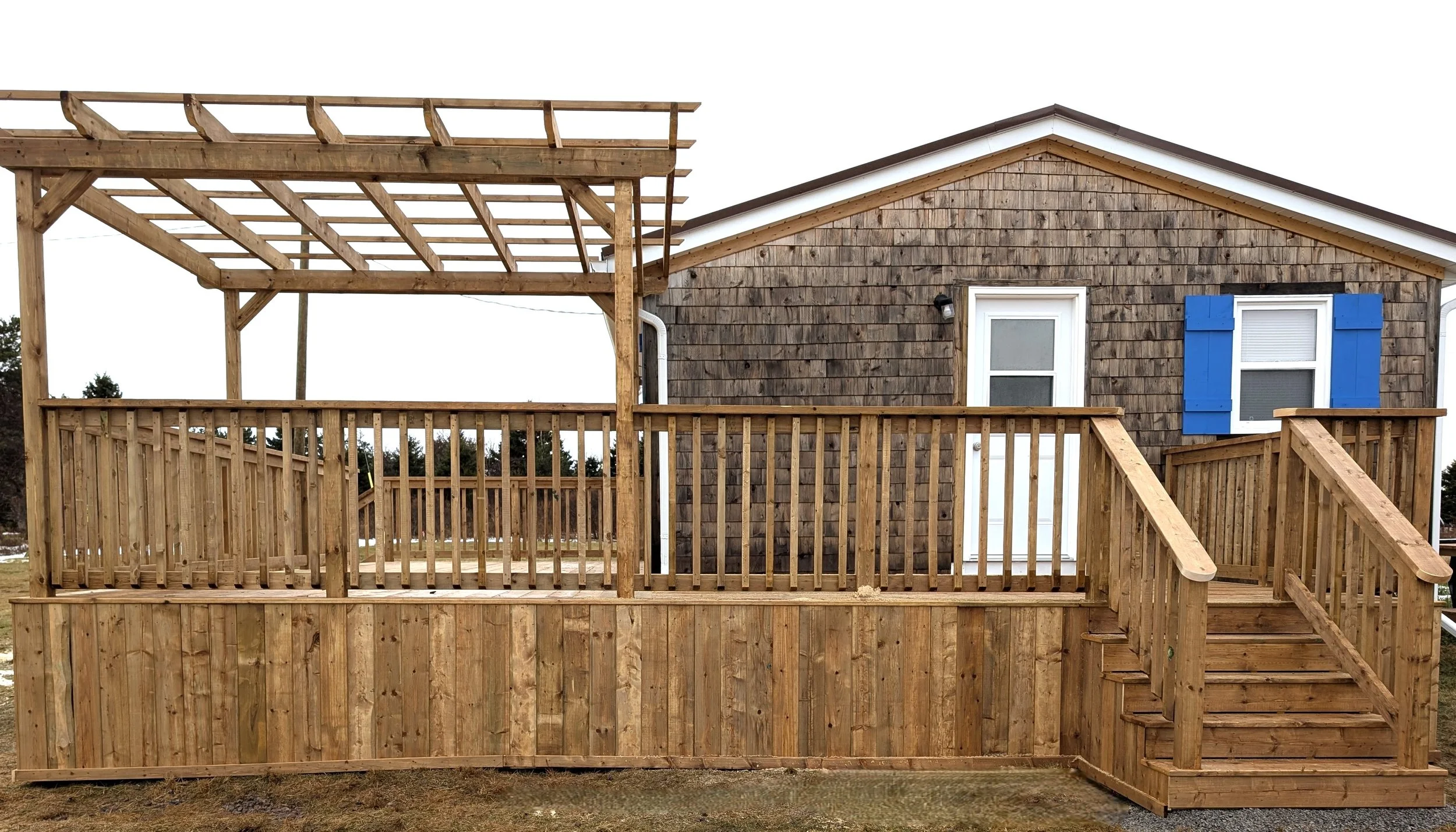 Completed pressure-treated wooden deck and railings with two sets of stairs, built in Canoe Cove, Prince Edward