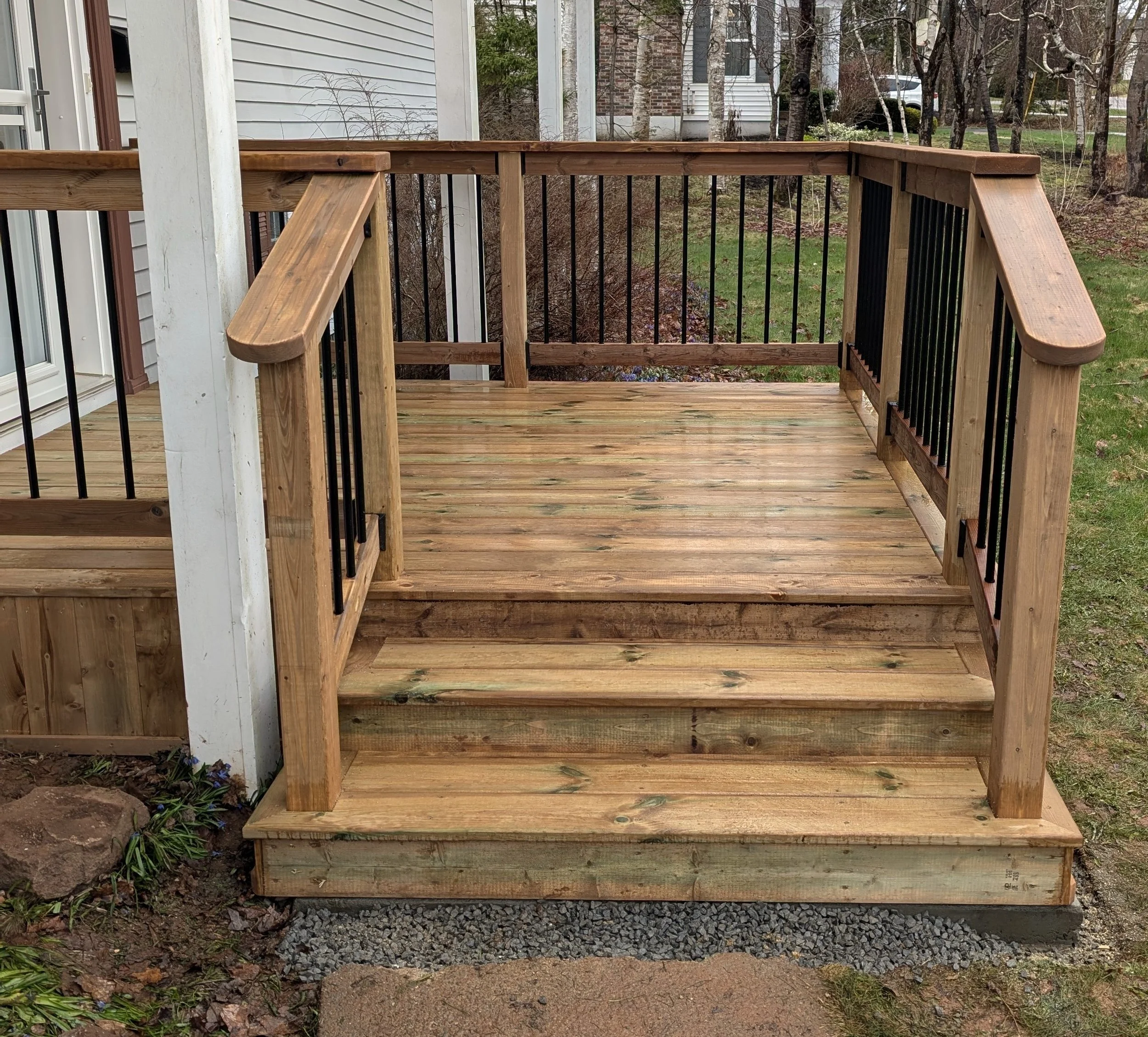 Custom design and built, pressure treated wooden, doorstep with stairs and black aluminum railing built for homeowner in Charlottetown, PEI