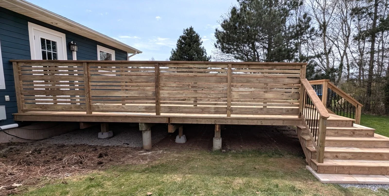 Custom pressure-treated wooden privacy wall on a wooden deck with cascading stairs built in Winsloe, PEI