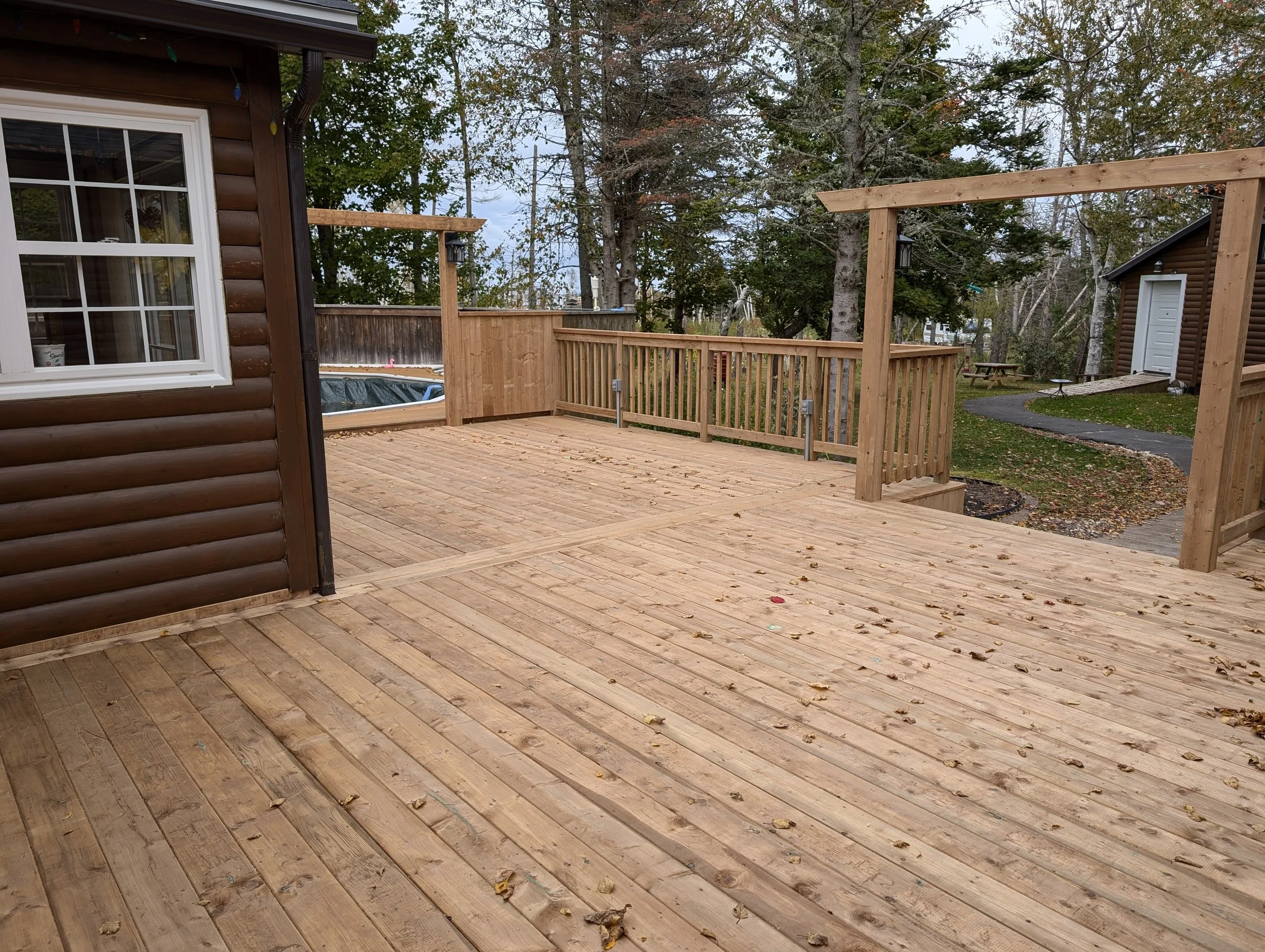 Custom built, pressure treated, multi-level wooden deck with wood railings, and inset step, built for a homeowner in Hunter River, PEI..