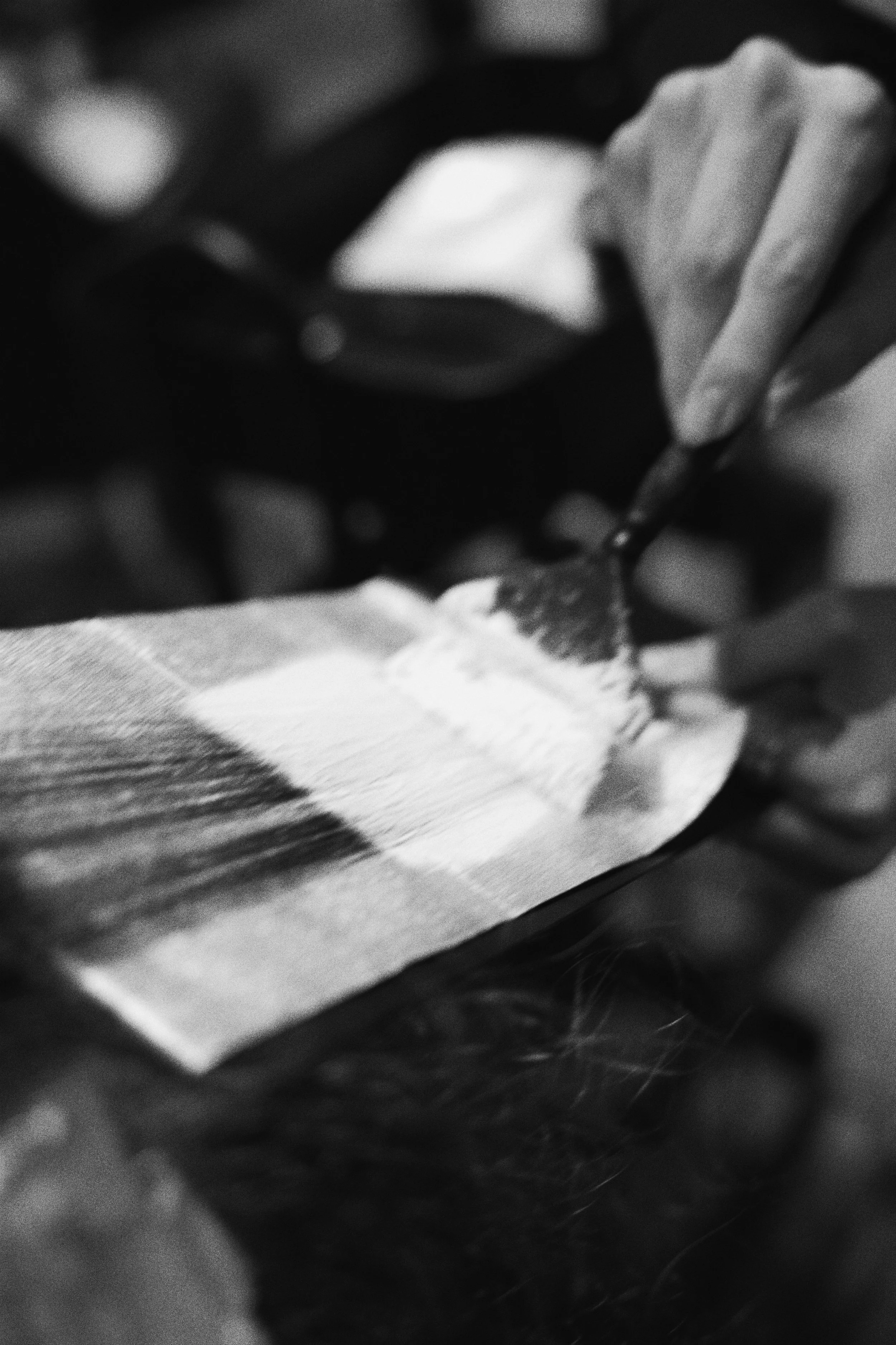 A close-up black and white photo of a person's hand coloring hair