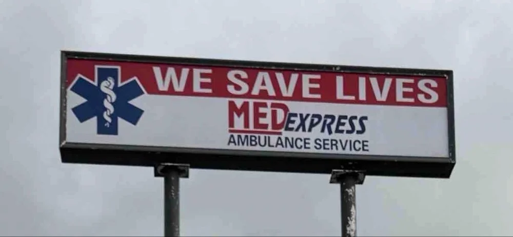 Billboard advertising MED EXPRESS ambulance service with a medical symbol and the slogan 'WE SAVE LIVES'.