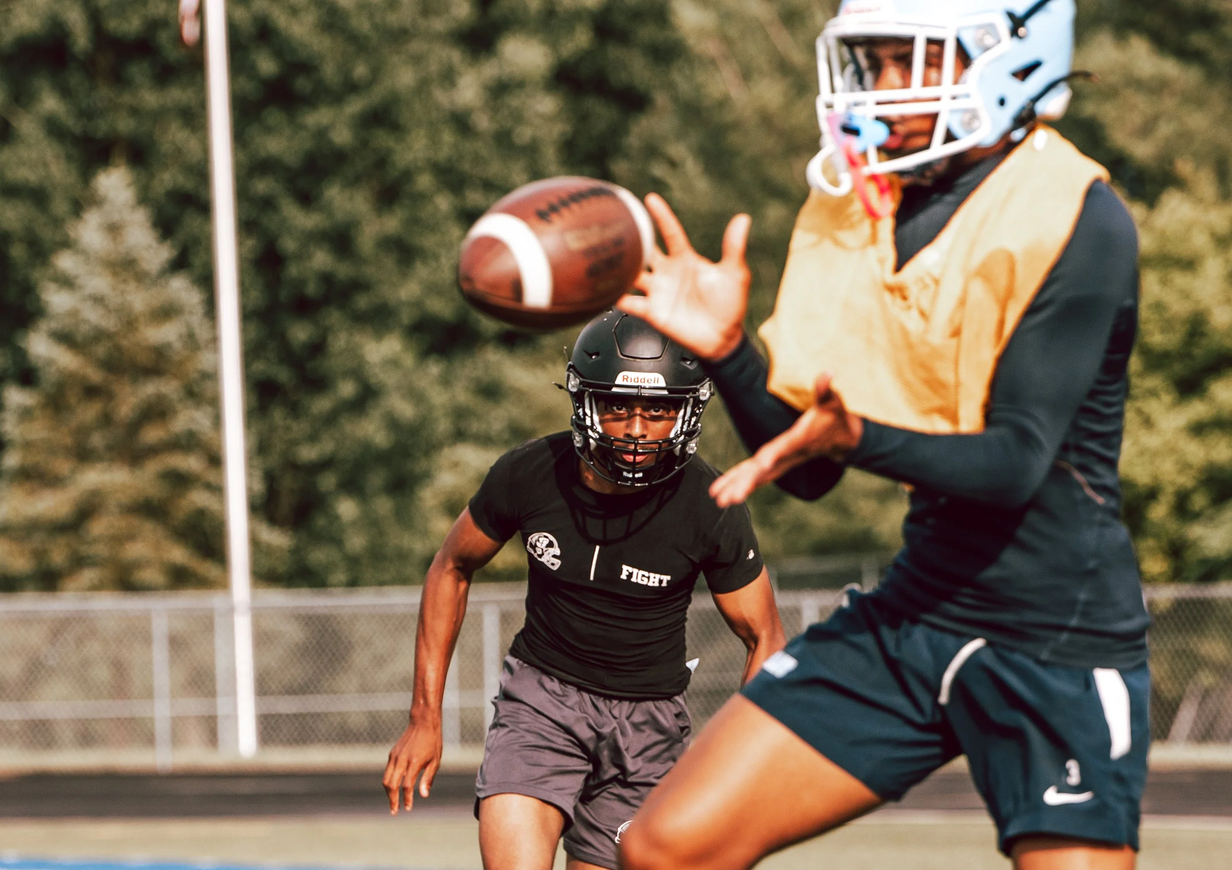 A football player catching a football during a game while another player looks on.