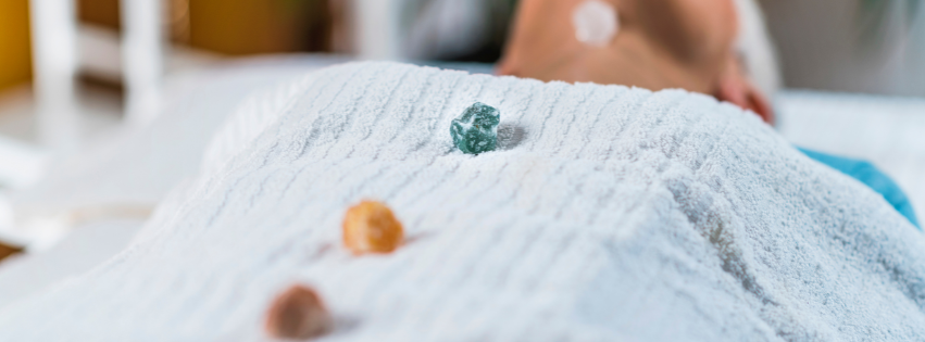 Close-up of a person lying on a massage table with crystals placed on her chakra points.