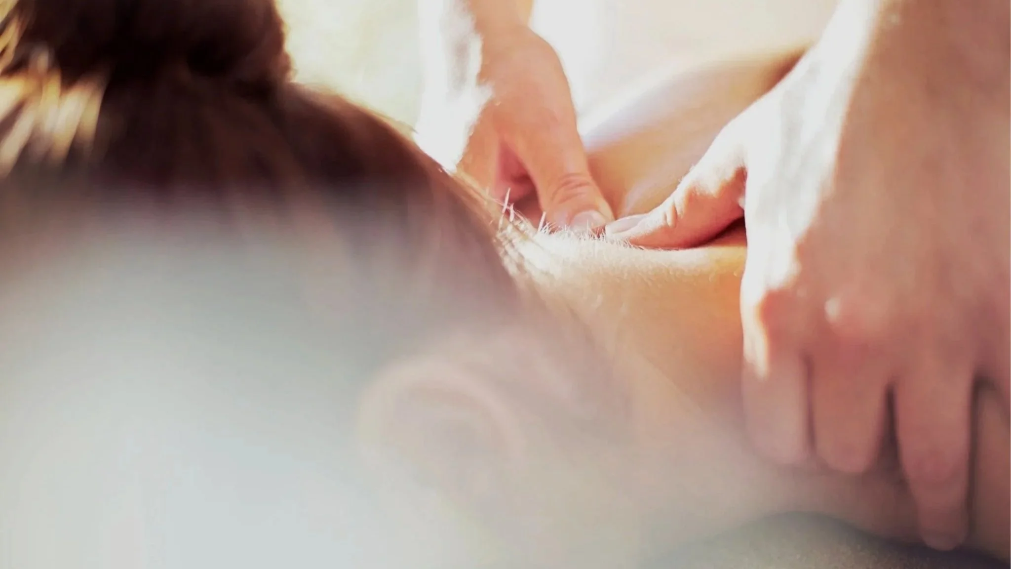 Close-up of a person receiving a massage with hands applying pressure on their back.