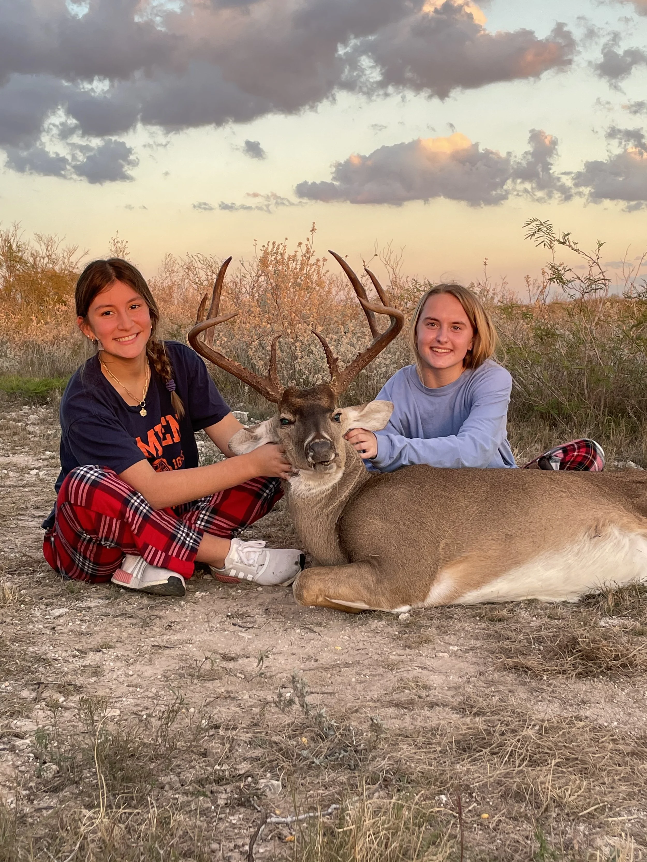 Two young women celebrating a successful deer hunt at Thermal Ranch in South Texas.