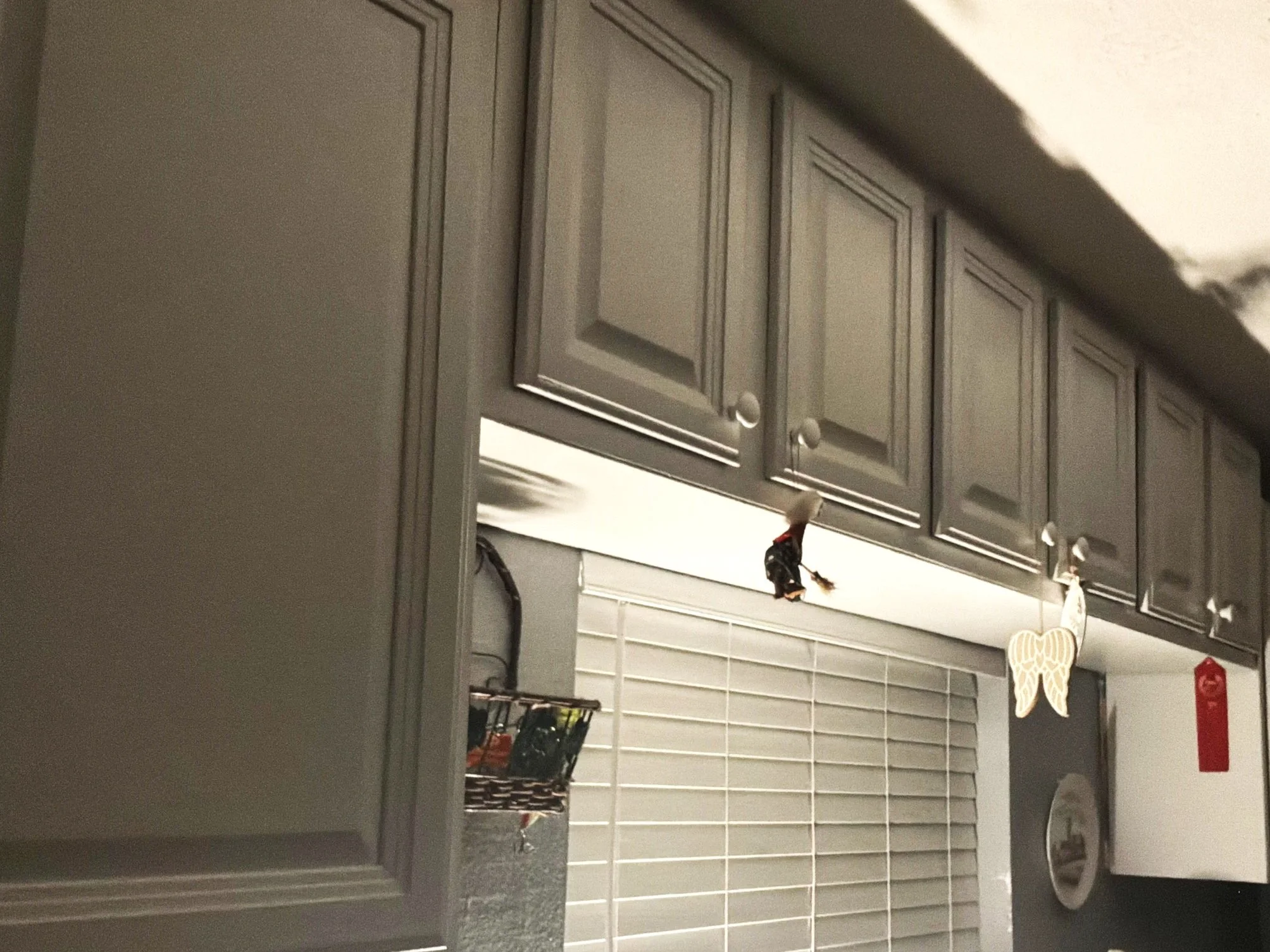 Kitchen upper cabinets and a backsplash with decorative hanging ornaments, including a giraffe and other animals, and a red fire extinguisher.