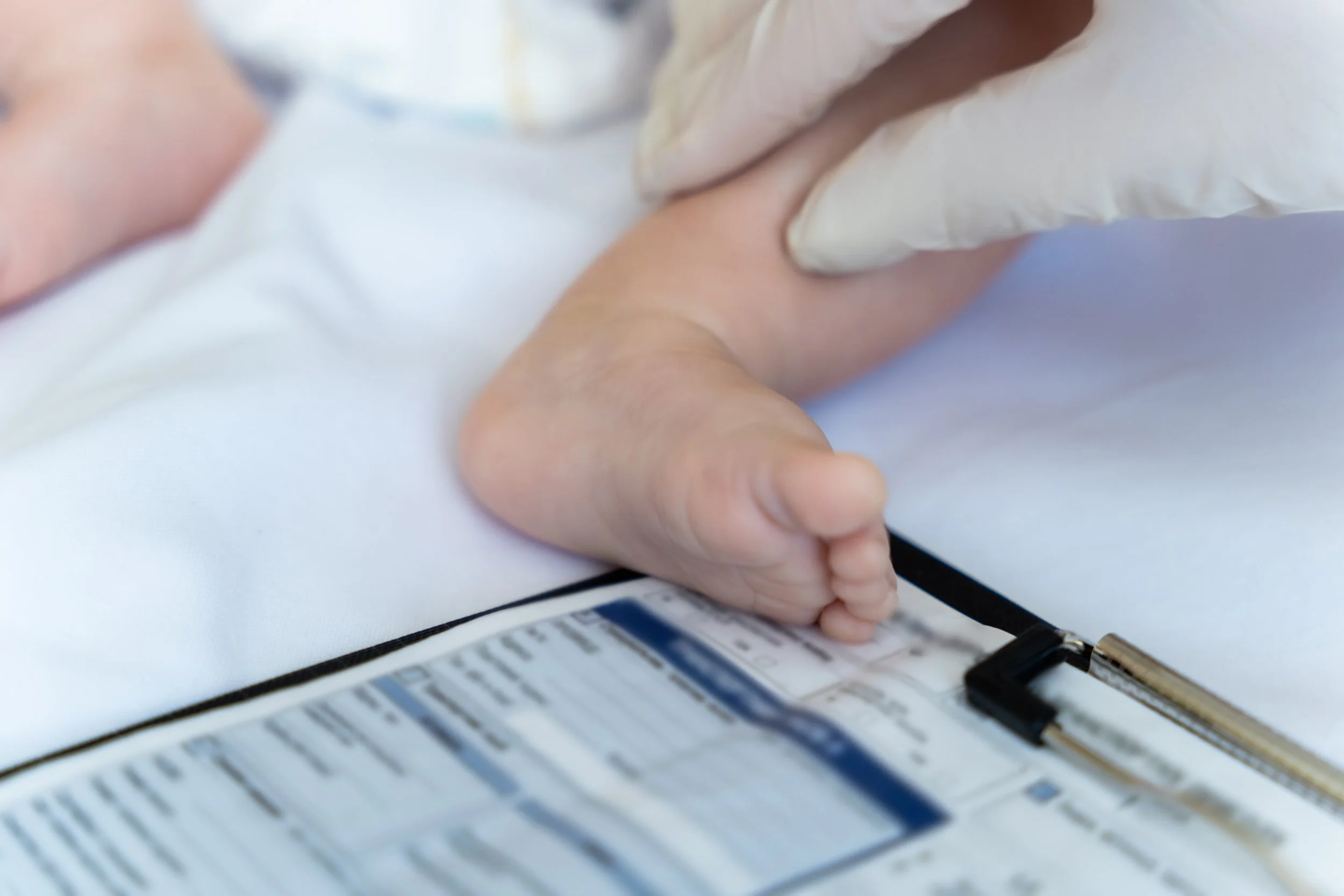 Close-up of a person's hand with medical gloves drawing blood from a patient's arm with a needle attached to a syringe.