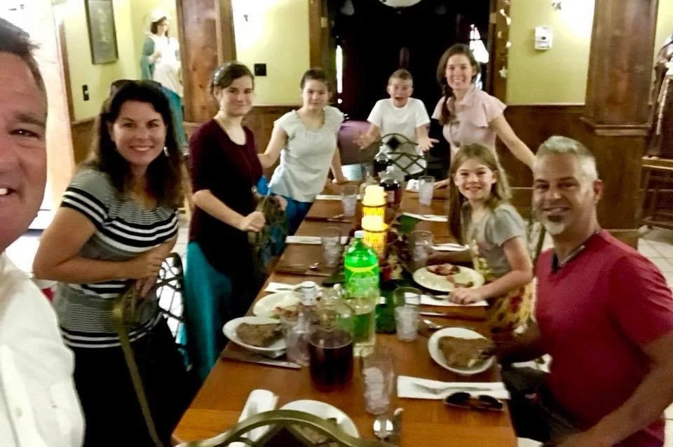 Family gathered around a dining table for a meal in a warmly decorated restaurant or home.