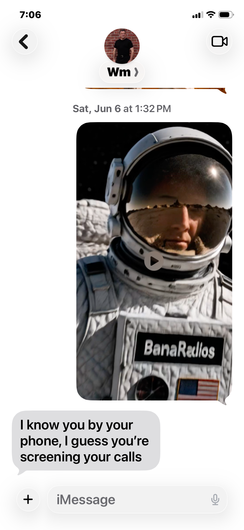 An astronaut in a spacesuit with the name"BamaRadios" and an American flag patch, taking a selfie on an extraterrestrial landscape with a reflection of a planet or moon in the helmet visor.