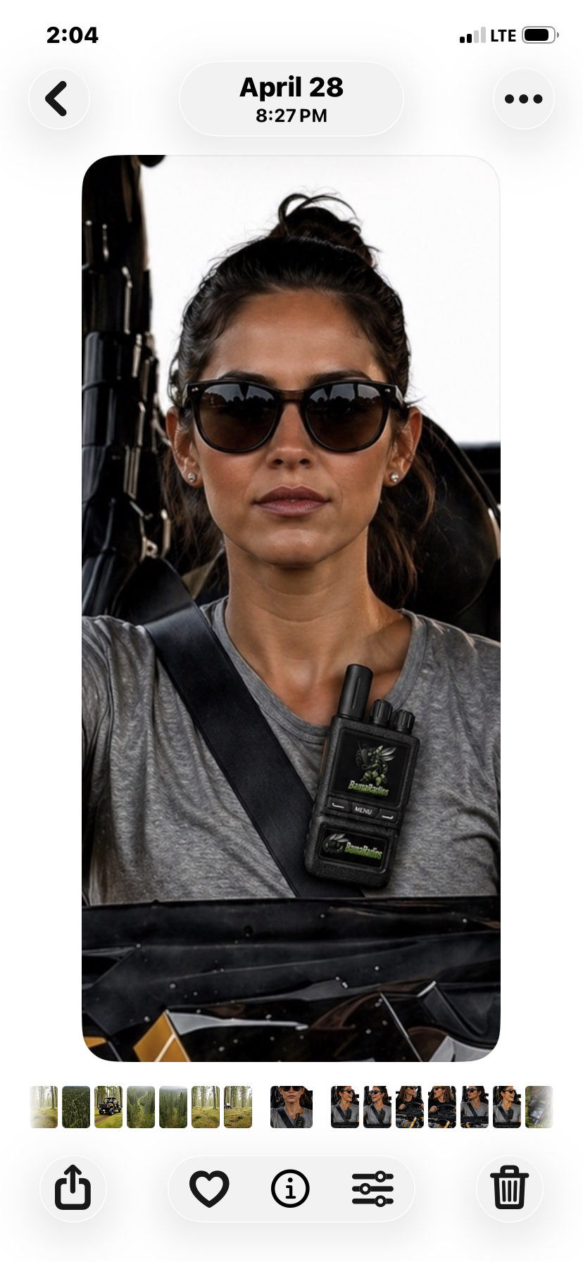 A woman wearing sunglasses and a gray shirt, with a walkie-talkie clipped to her shirt, sitting on a motorcycle.