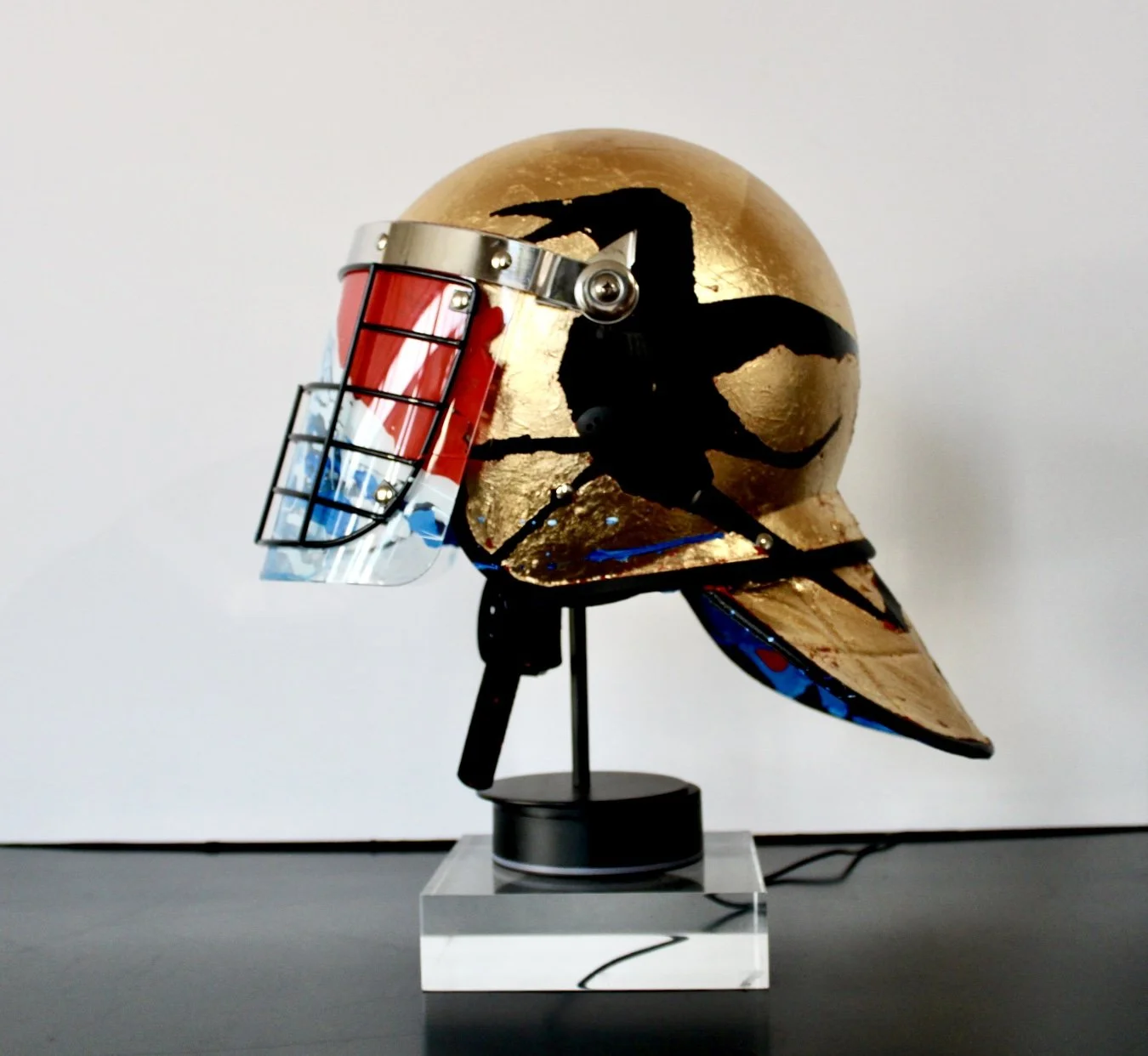 "When the Mountain Blesses the Rain" [side view]

Acrylic and Imitation Gold Leaf on Police Riot Helmet
18" x 12" x 10.5"
2024