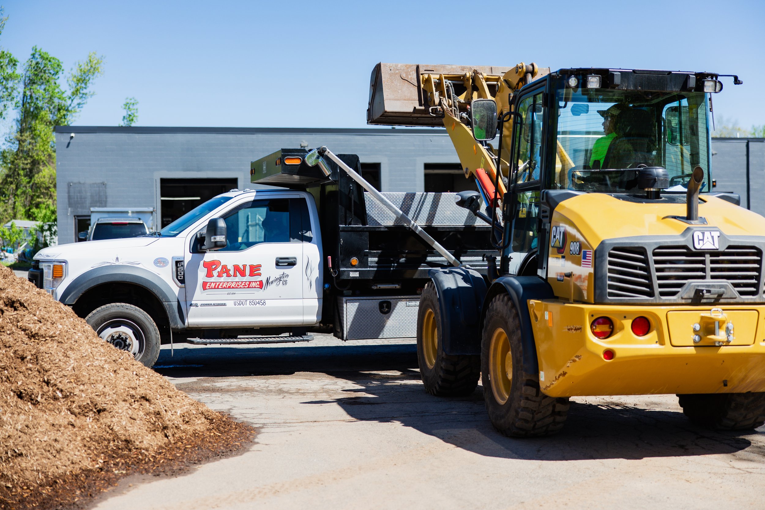 Construction site with excavation equipment and a pickup truck, under a clear blue sky.