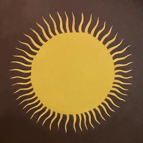 Yellow sun with wavy rays on a dark background.