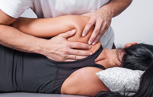 A healthcare professional performing a physical examination on a patient's back.