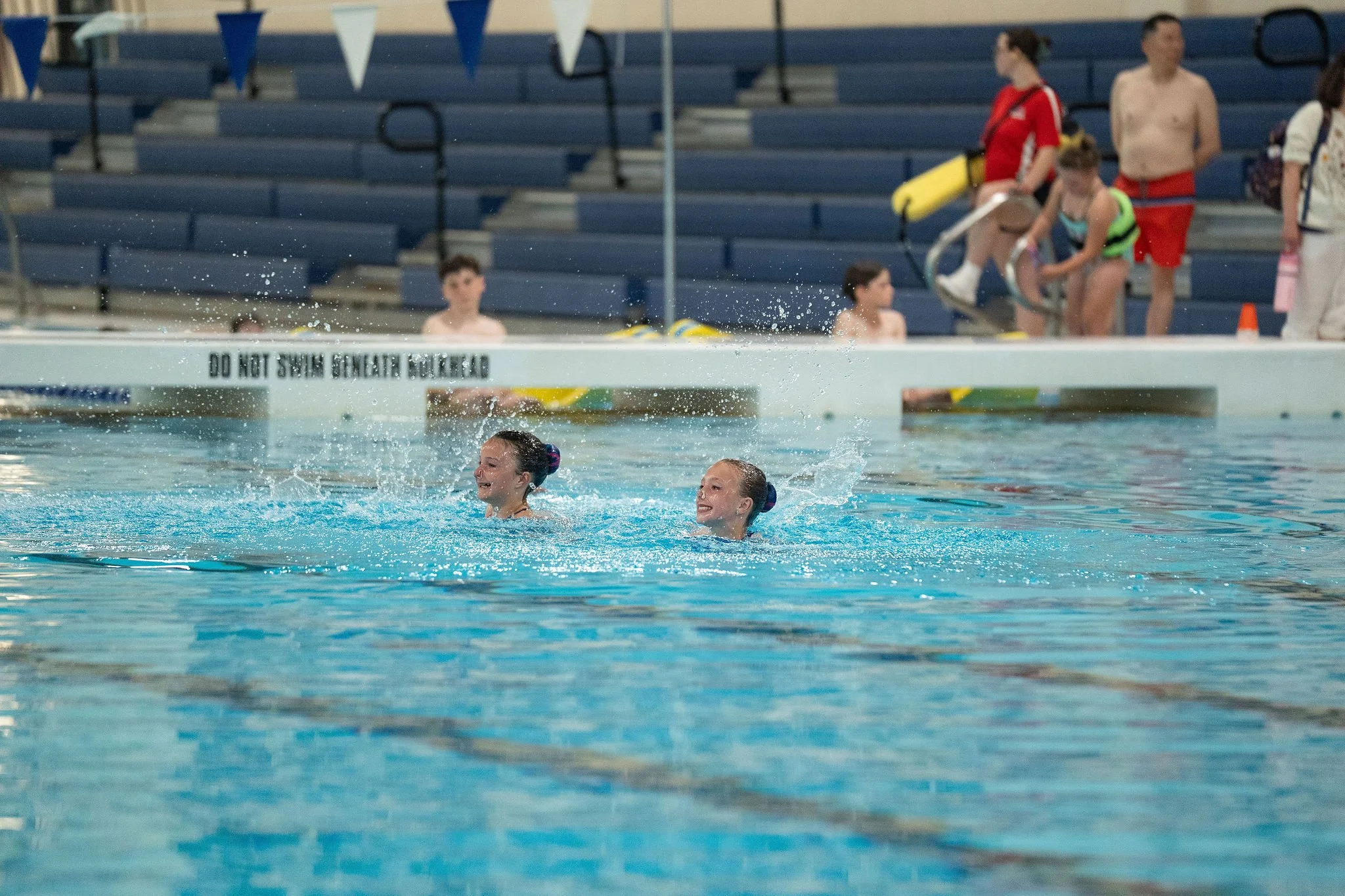Two swimmers in the pool with smiling while performing.