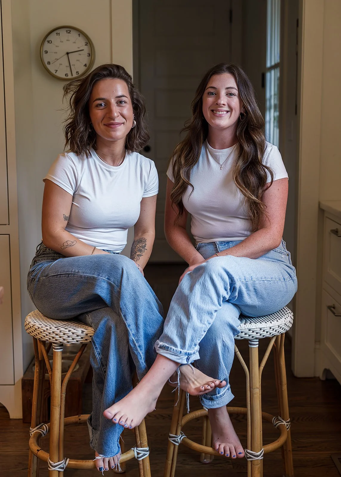 Founders of Clean Living Co, a family-focused cleaning company specializing in low-tox cleaning sitting on stools smiling.