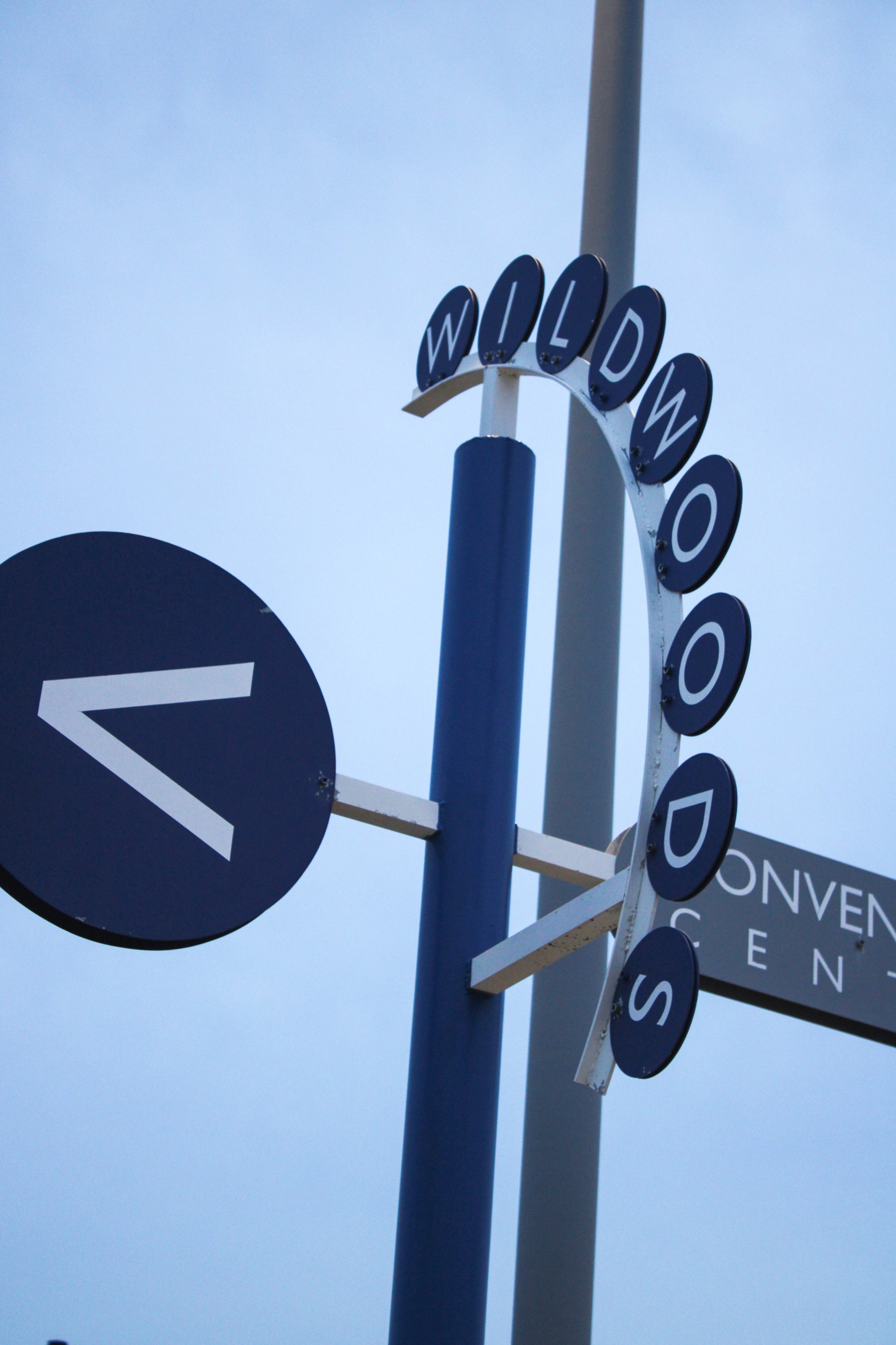 Street sign with the word 'WILLOW' on top and directional signs below, part of a road or city signpost against a cloudy sky.