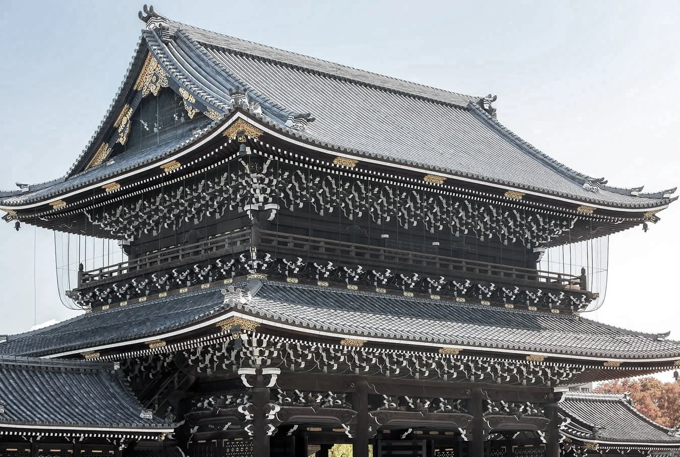 Traditional Japanese temple with multiple-tiered roof, black and gold details, and intricate woodwork.