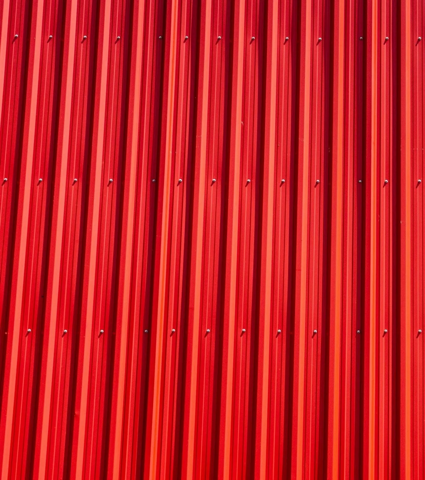 Close-up view of a red corrugated metal wall with vertical ridges and small bolts.
