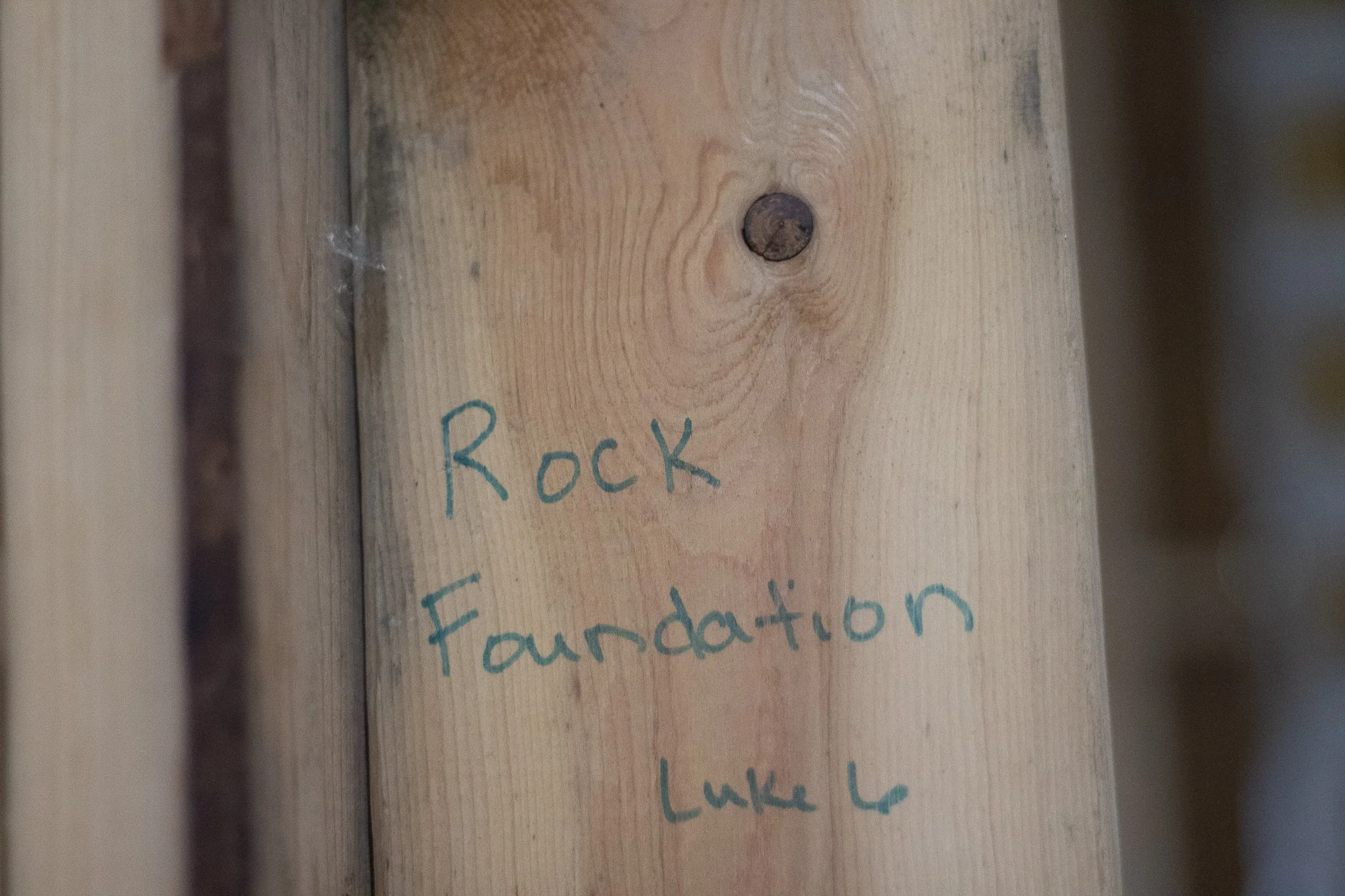 Close-up of wooden surface with handwritten text that says "Rock," "Foundation," and part of other words.