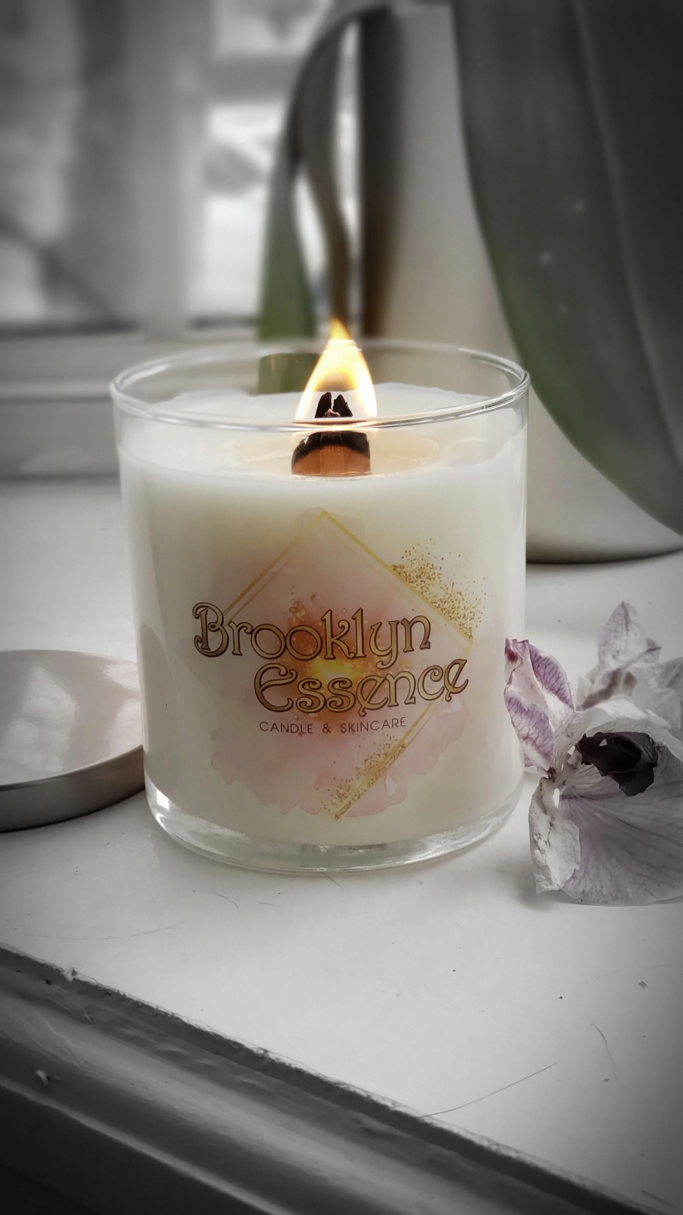 A lit white candle in a glass container with
