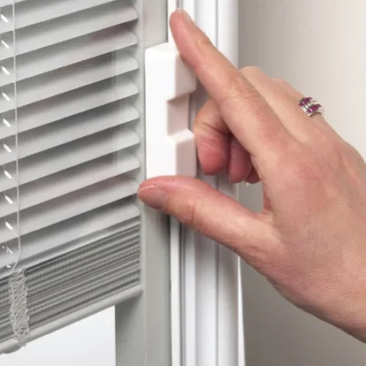 A hand with a ring on the finger adjusting a white window or door latch.