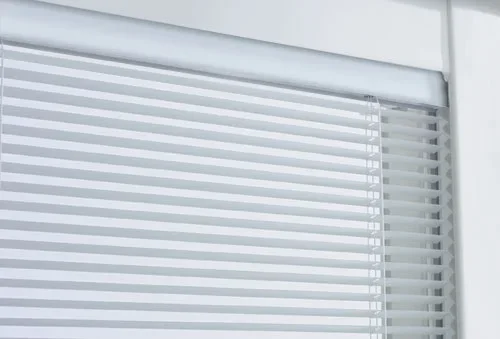 Close-up of white horizontal window blinds with a partially open window frame.