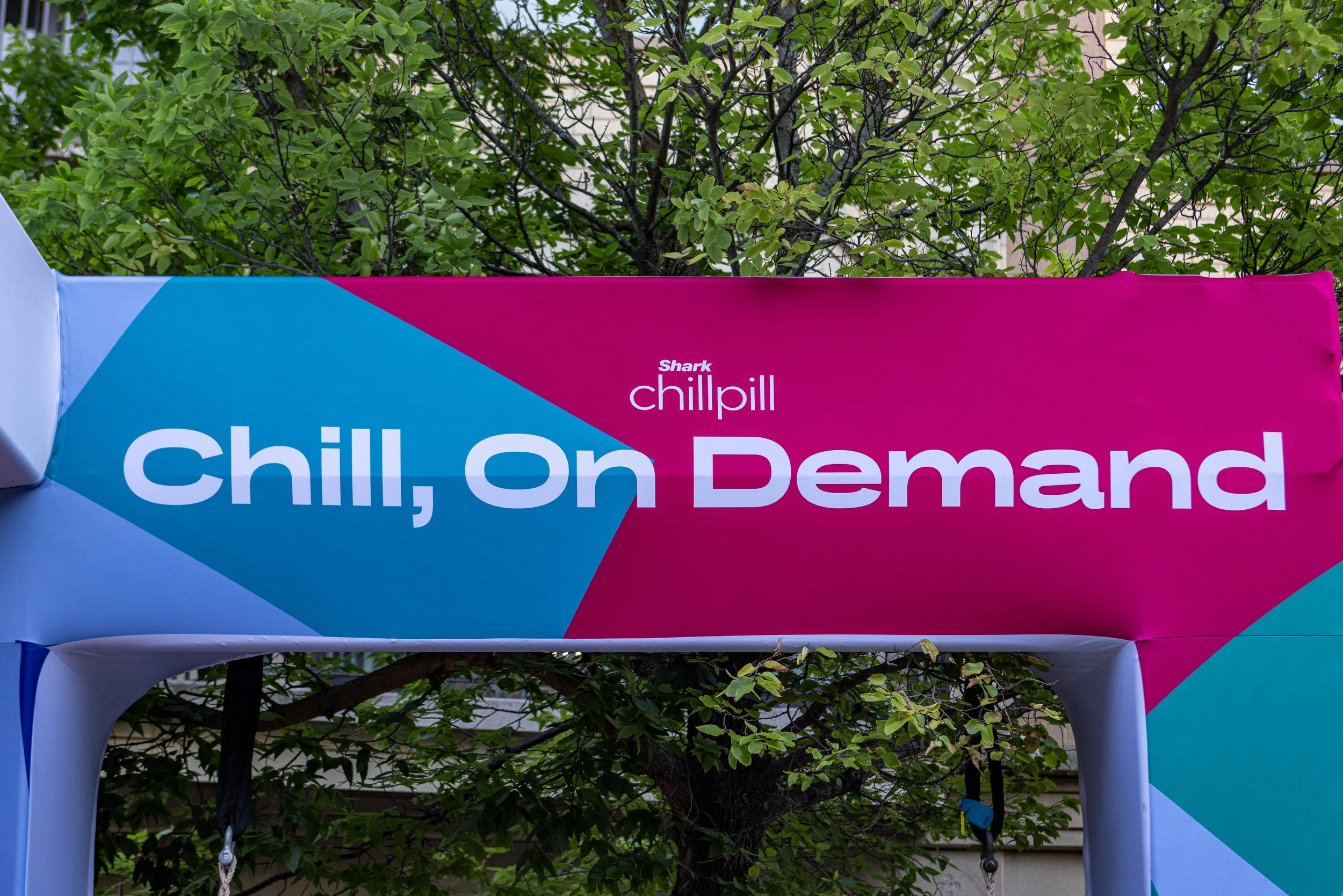 A colorful sign that says 'Chill on Demand' with a background of green tree leaves.